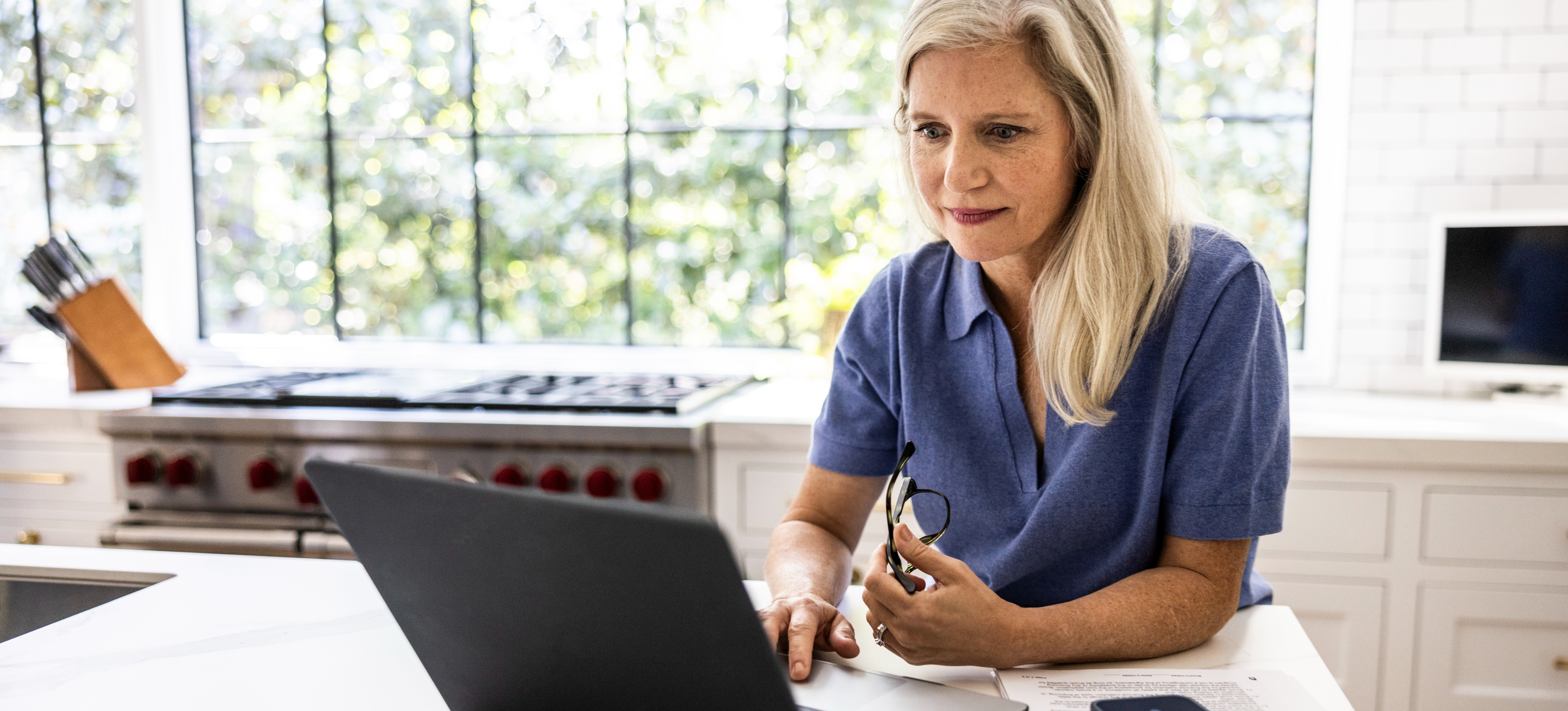 [Featured Image] A person sits at their sunny kitchen counter researching what master's degree they should get on their laptop.