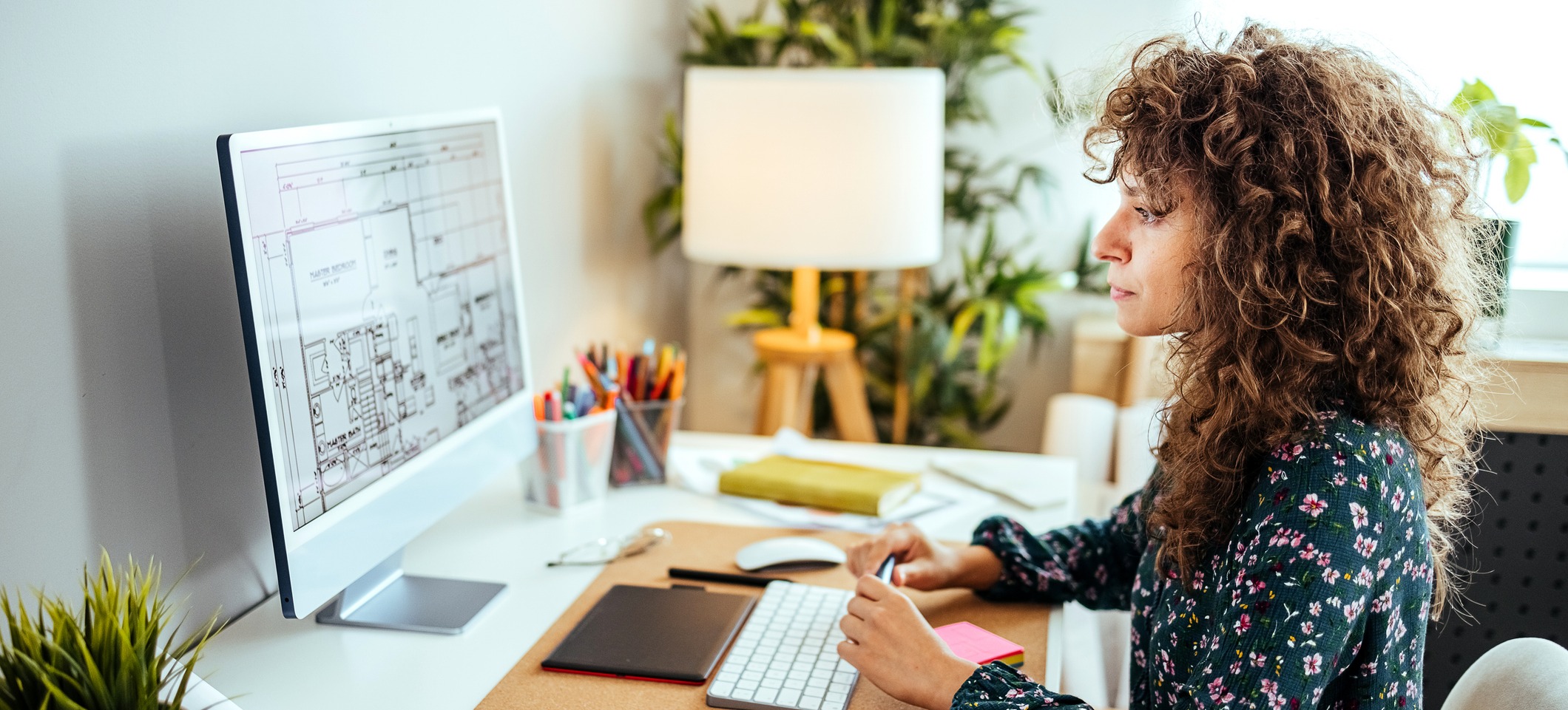 [Featured Image] An architect uses ethical design principles as they create a design and view it on a computer screen in a home office.

