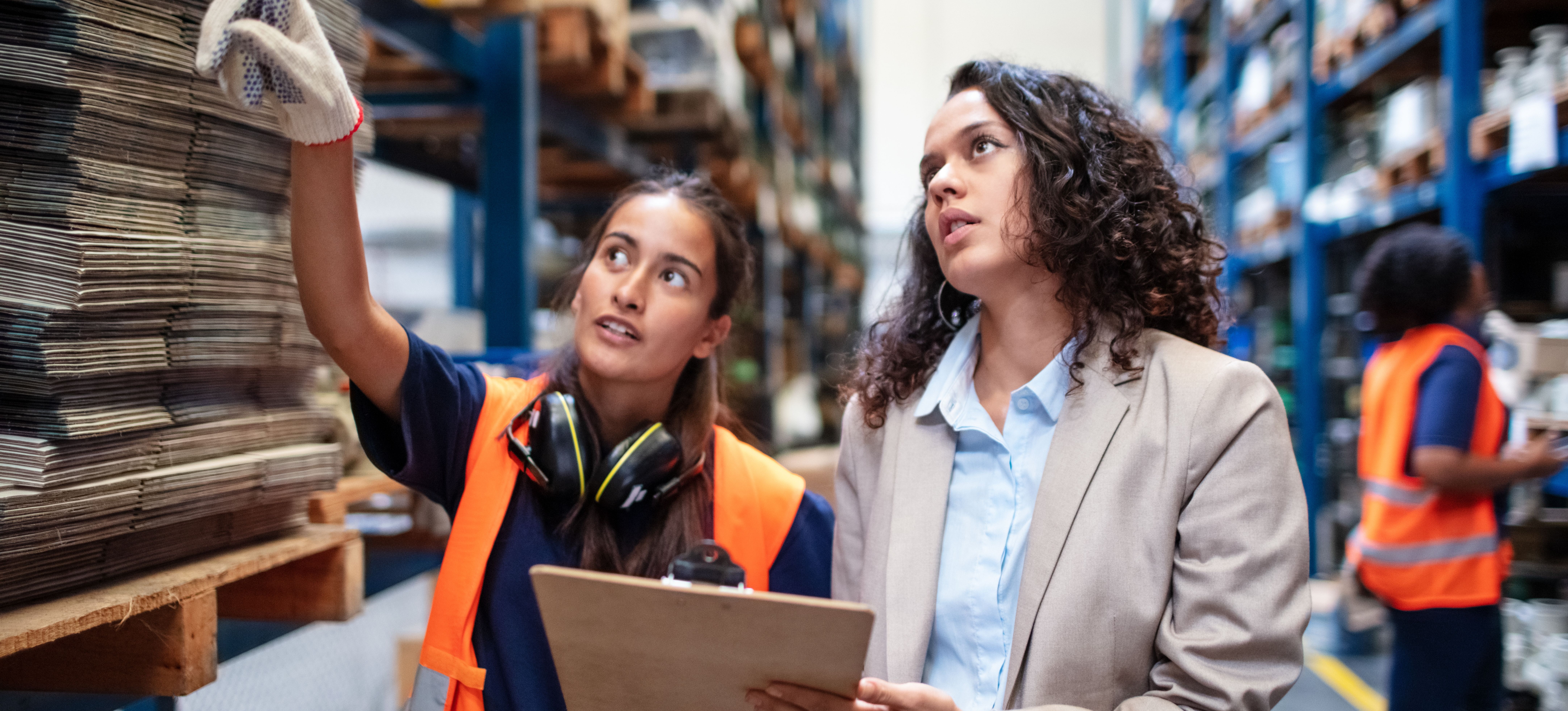 [Image en vedette] Deux ouvriers sont chez un fournisseur de matériaux et discutent de ce dont ils ont besoin. L'une d'elles tient un presse-papiers tandis que l'autre pointe du doigt les matériaux.