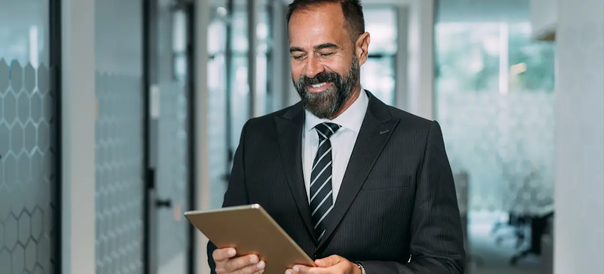 [Featured Image] A businessperson holding a tablet and smiling in a professional setting, representing strategies for securing a high-paying job.
