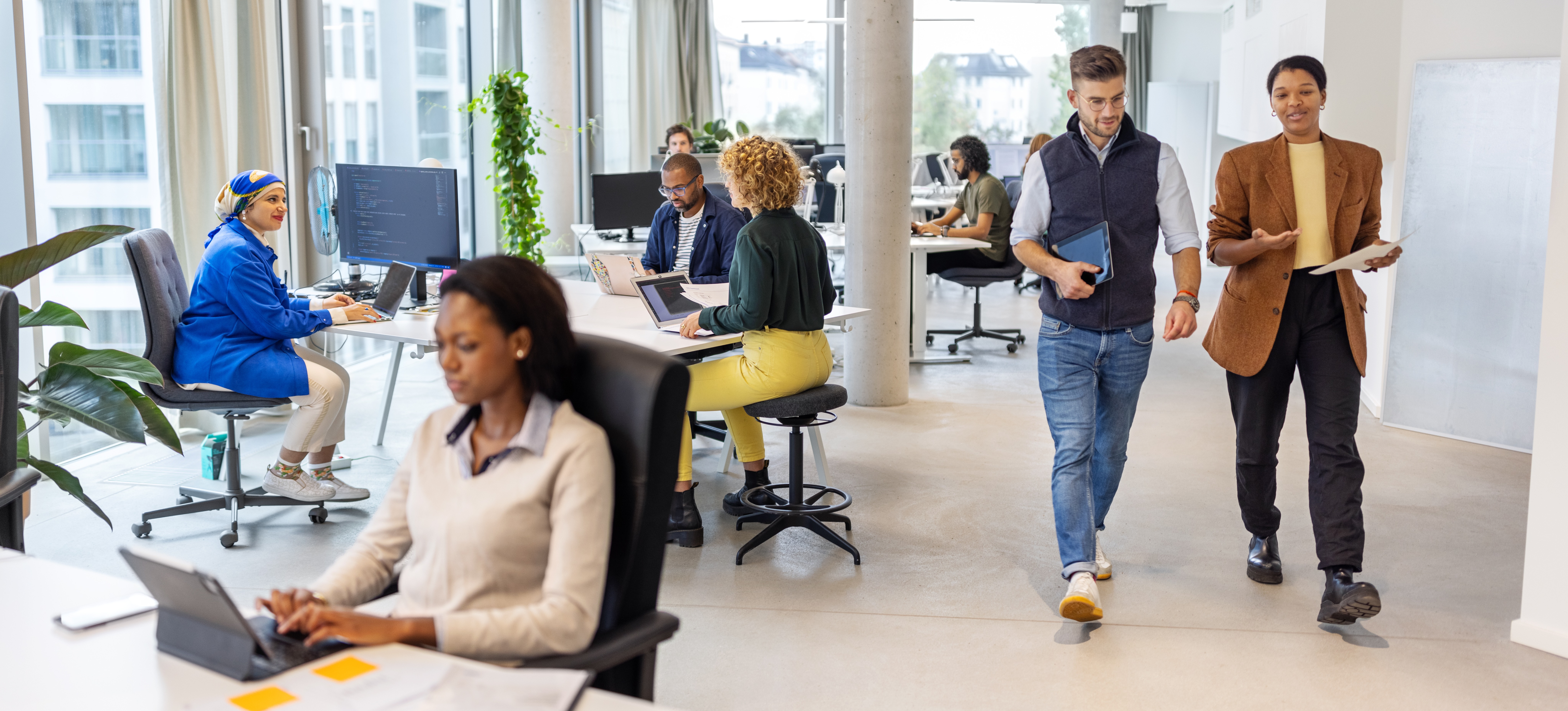 [Feature Image] Two machine learning engineers walk through a business office while discussing object detection vs. image classification to choose the method best suited to their project.
