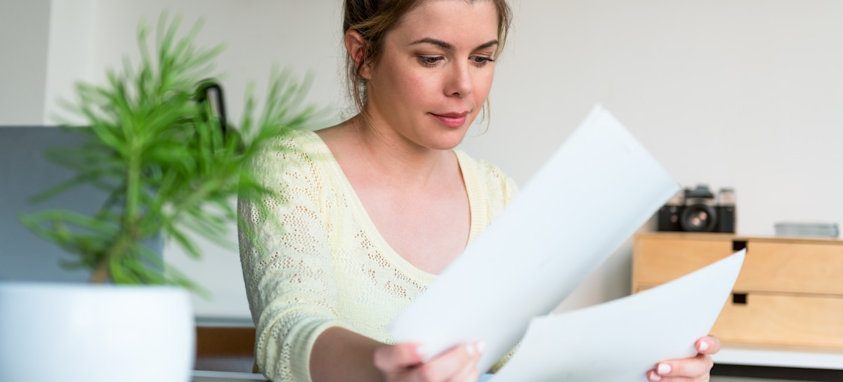 [Featured image] A person in a pale yellow sweater sits at a table and looks over a two-page resume. There's a plant on the table in front of them.