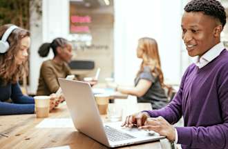 [Featured image] A cloud security engineer wears a purple sweater and works on their laptop at a coffee shop.