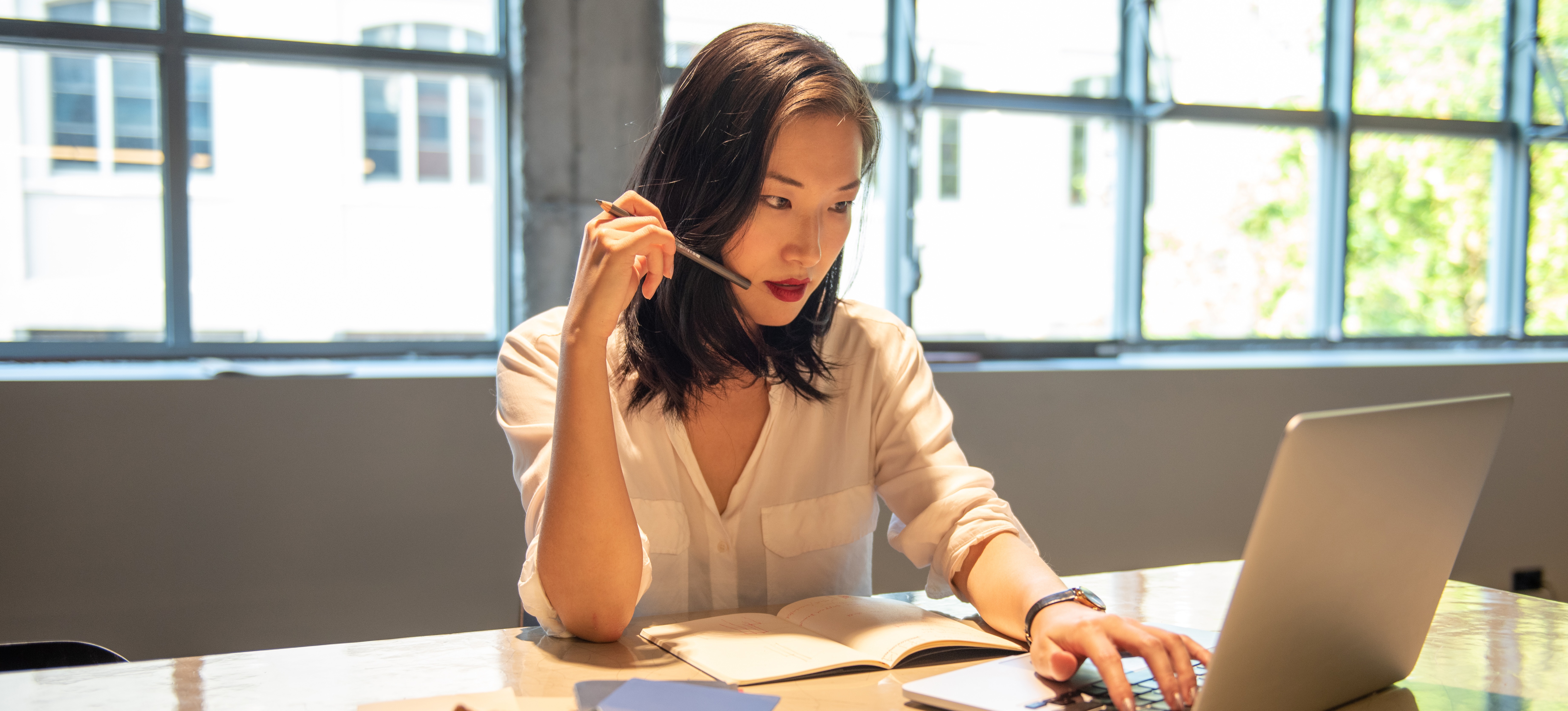 [Featured image] A person sitting next to windows inside a library researches how to boost their Google Ads optimization score on their laptop.