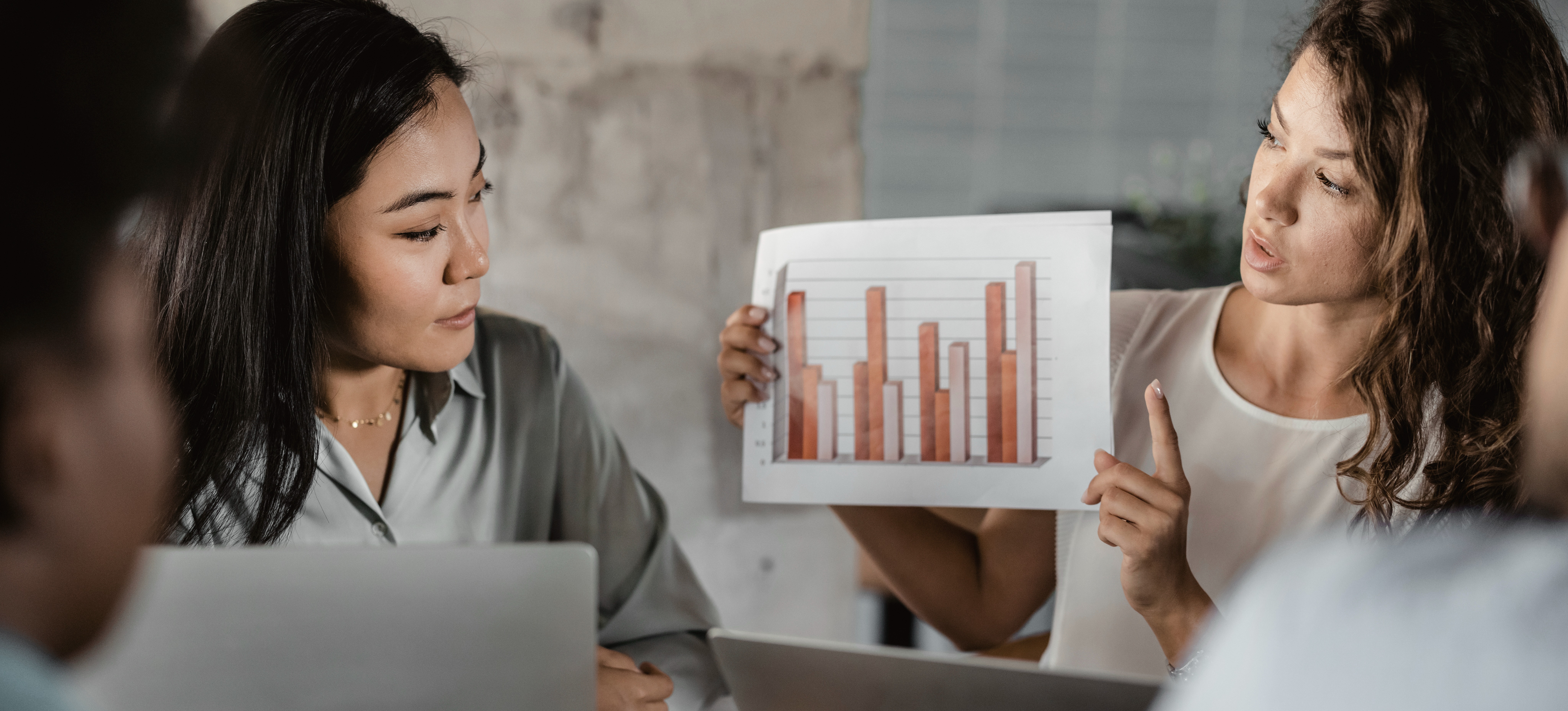 [Featured Image] Two business people presenting a predictive analysis as a graph.
