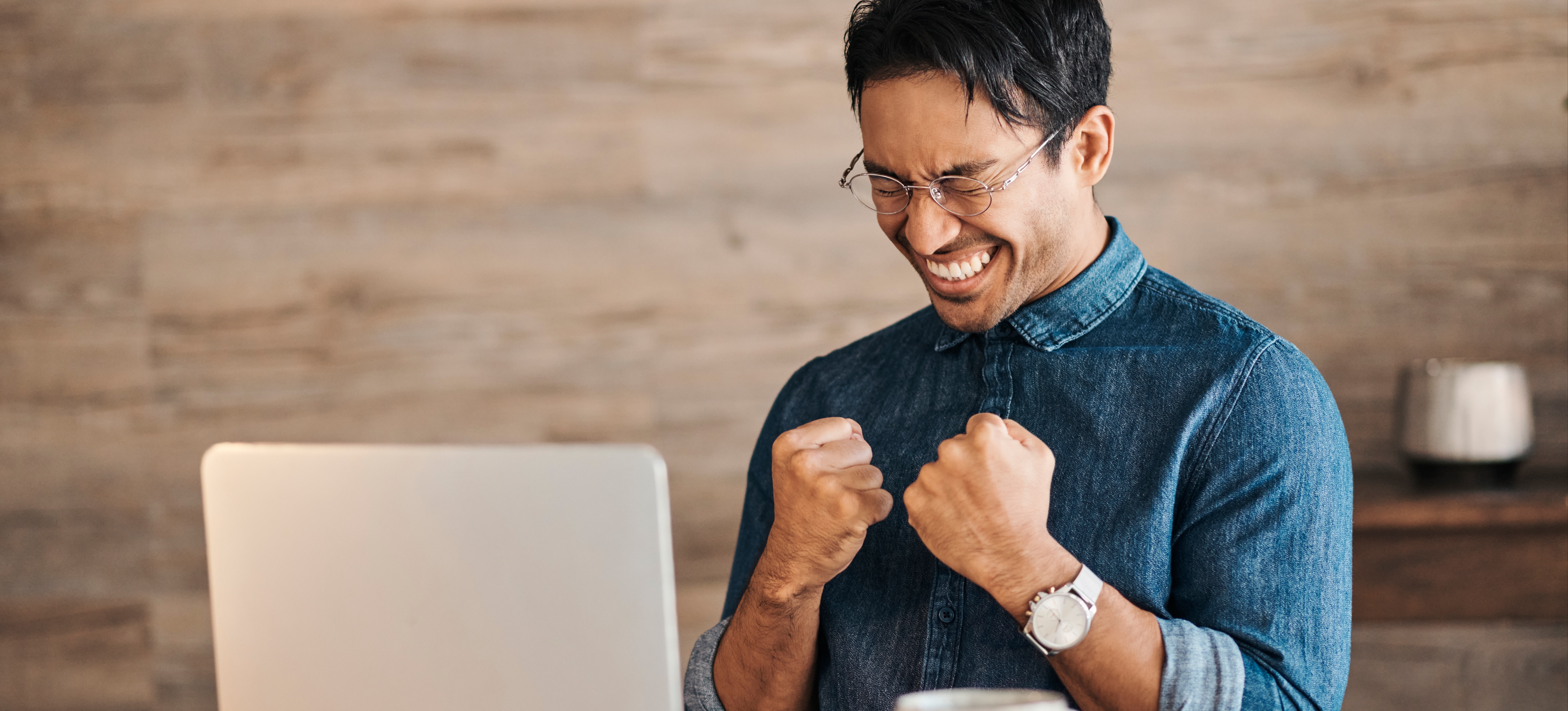 [Featured Image] A person sitting at a laptop celebrates a job offer received after they learned how to get a job at Google.
