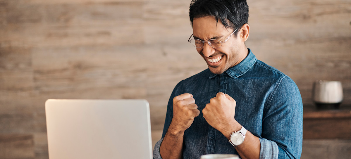 [Featured Image] A person sitting at a laptop celebrates a job offer received after they learned how to get a job at Google.

