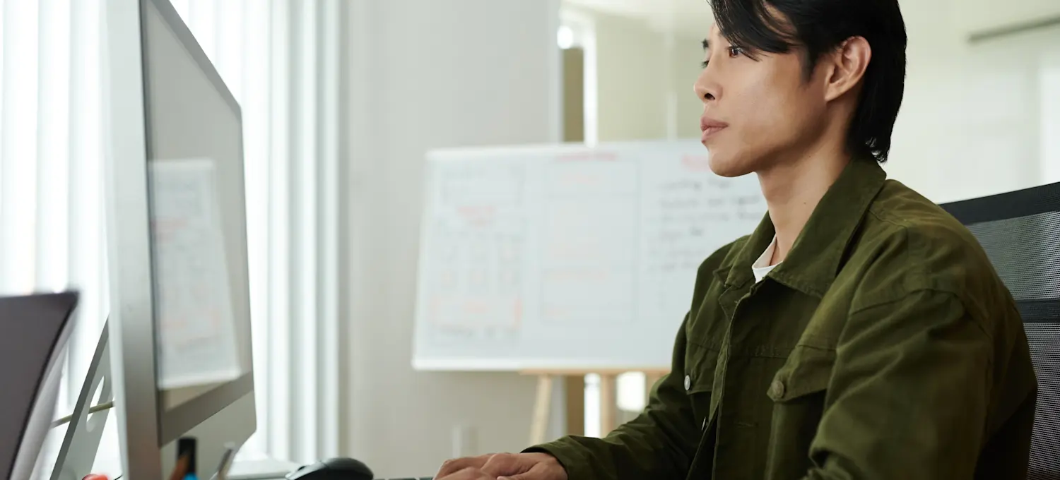 [Featured Image] A cloud engineer researches the best way to learn Kubernetes on their computer in a well-lit office space.