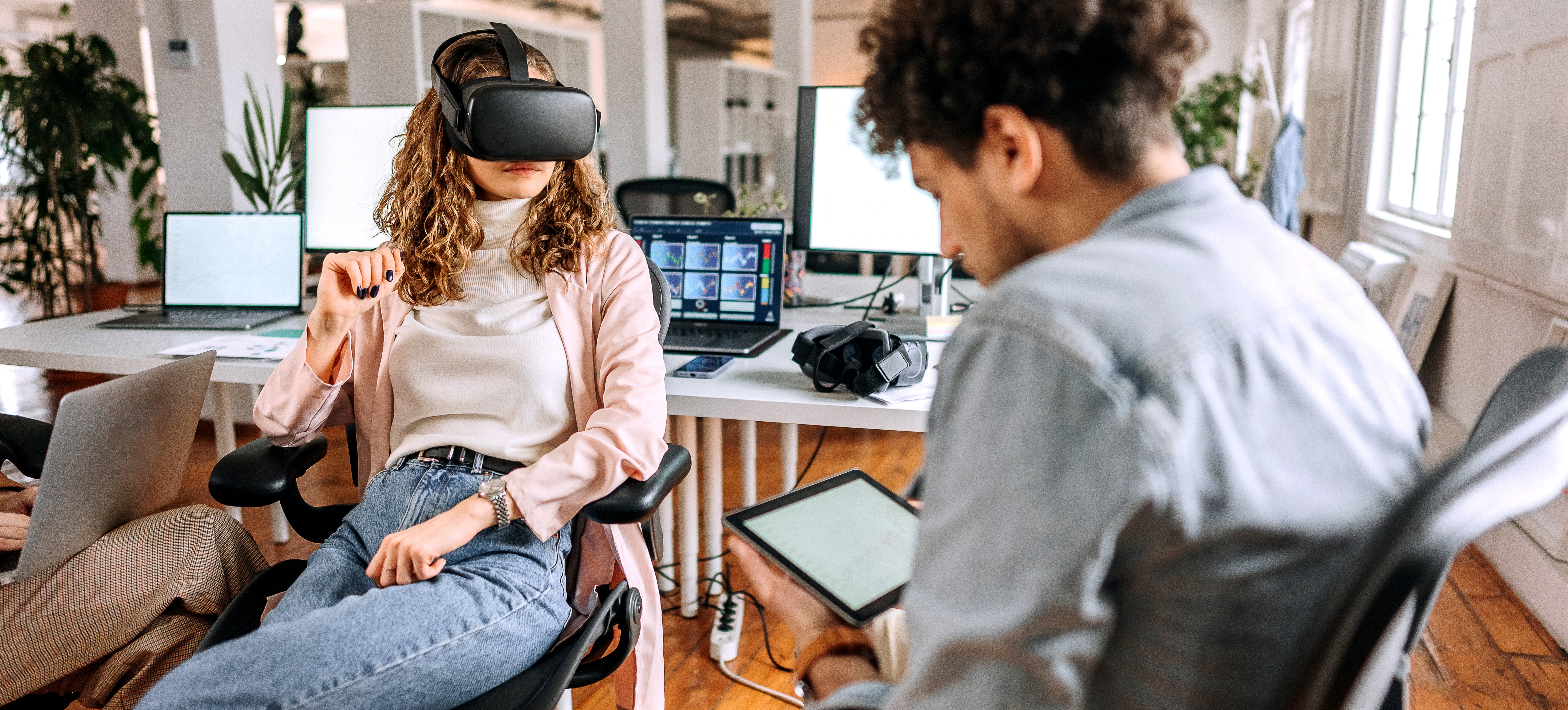 [Featured Image] Two colleagues at a VR company test new technology. 