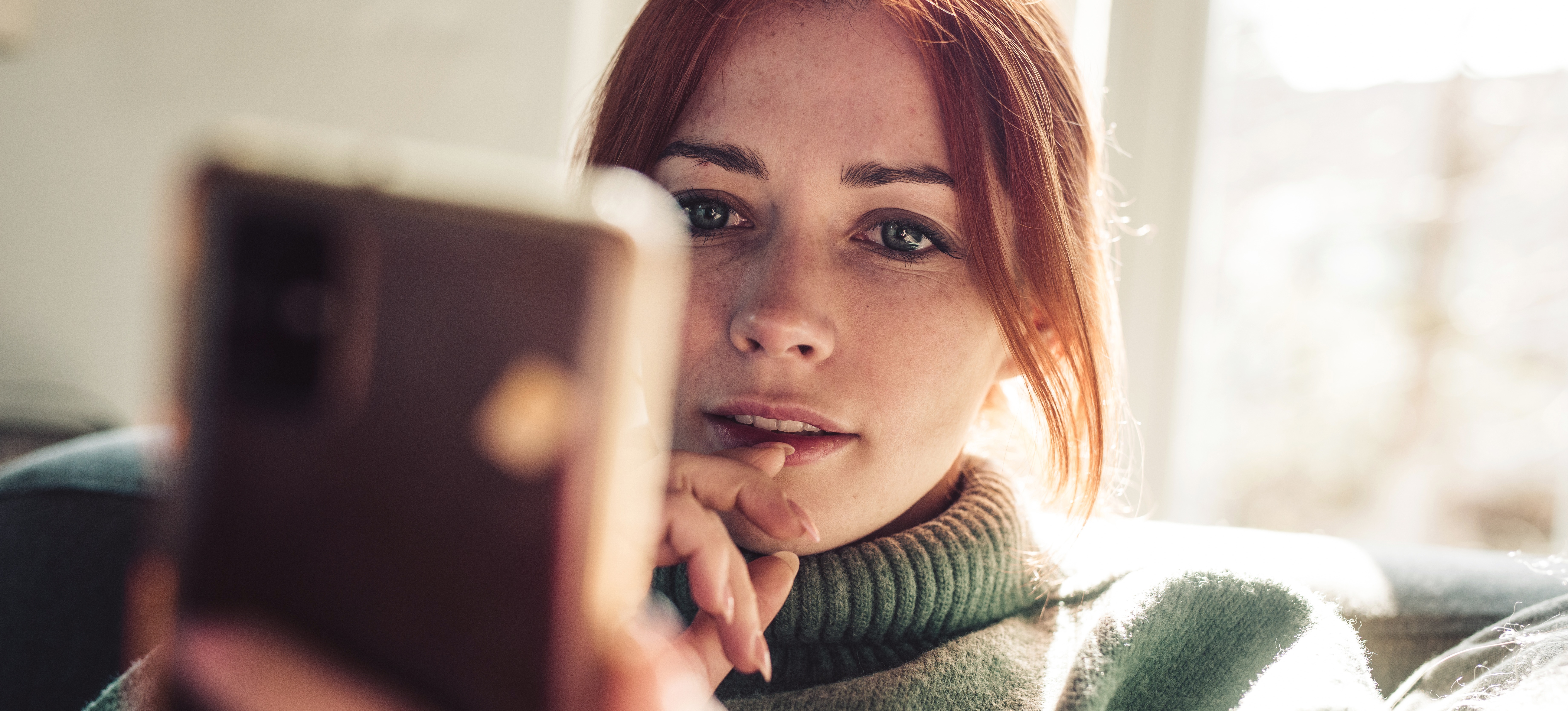 [Featured Image] A person with red hair is looking at the screen of their smartphone at product recommendations that have been suggested using machine learning algorithms.