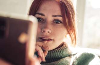 [Featured Image] A woman with red hair is looking at the screen of her smartphone at product recommendations that have been suggested using machine learning algorithms.