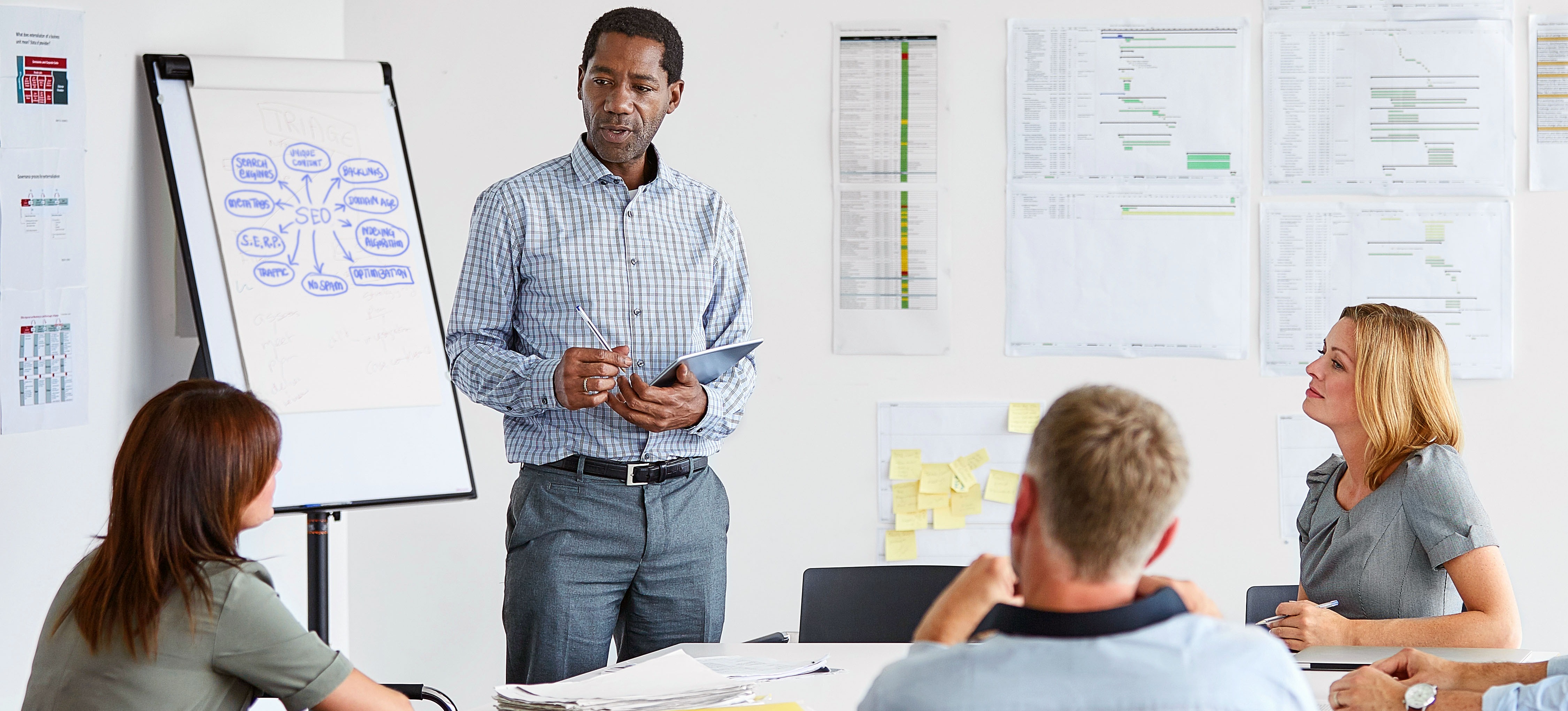 [Featured image] An SEO marketer presents a chart to a group at a conference table.