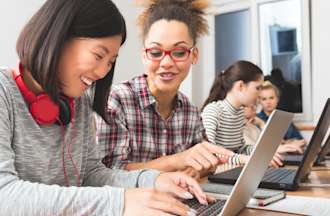 [Featured Image] Two women work side by side on laptop computers.