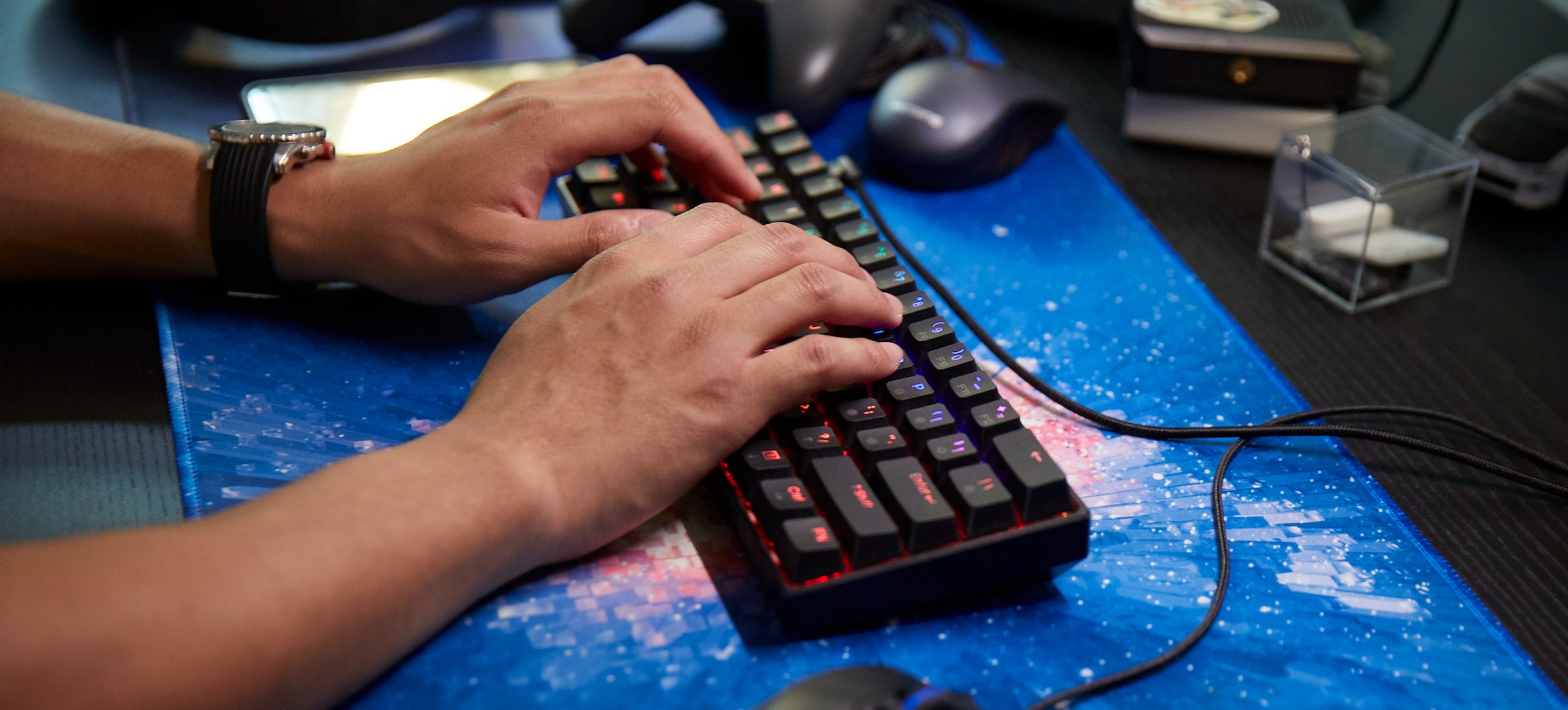 [Featured Image] Two hands type on a desktop keyboard as a person uses VLOOKUP in Google Sheets.