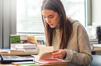 [Featured image] An aspiring project manager looks through several project manager books as she studies for the PMP.