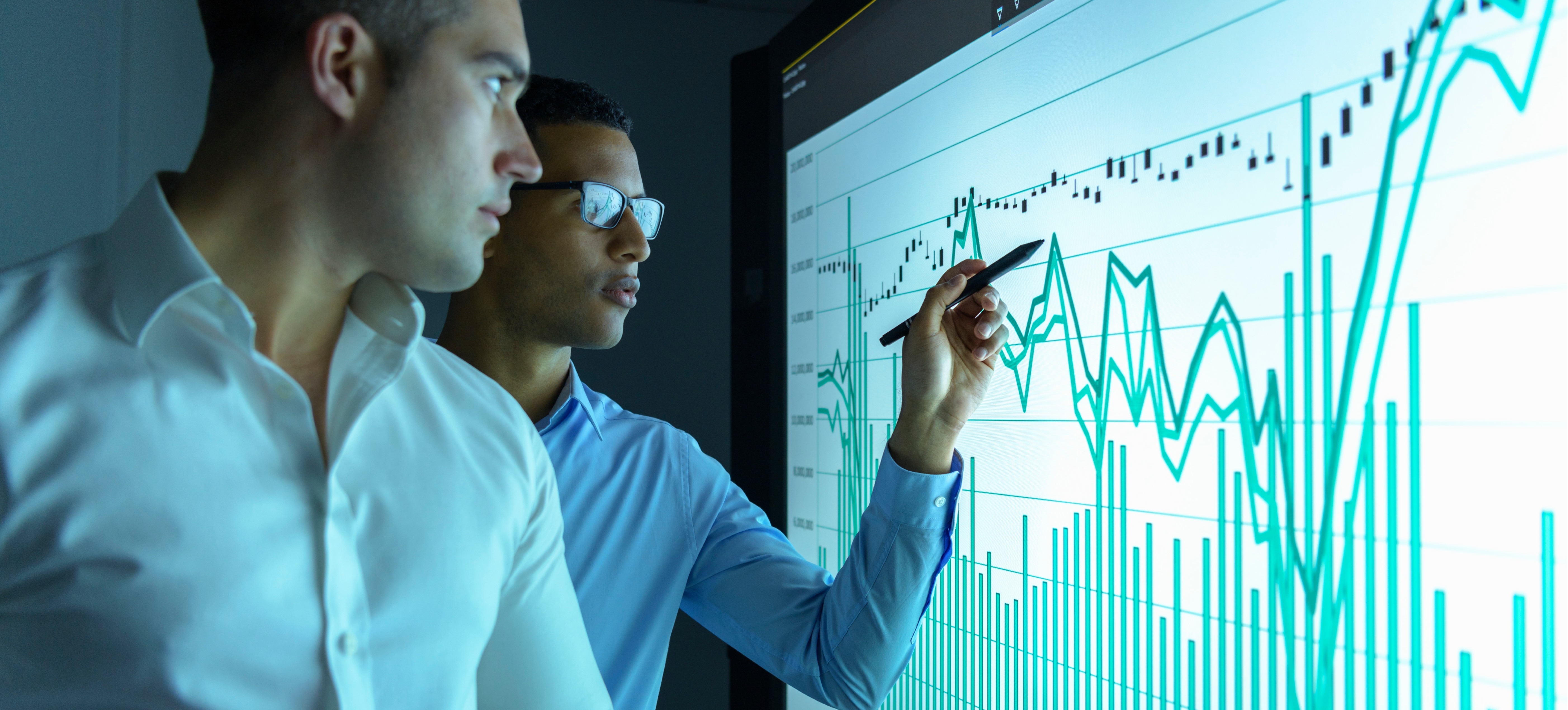 [Featured Image] Two businessmen study an interactive screen that displays a graph formed by discrete or continuous data.