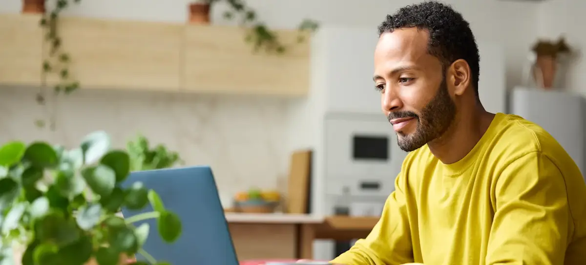 [Featured Image] A person sits at a table at home working on a laptop, learning how to use ChatGPT to generate images.