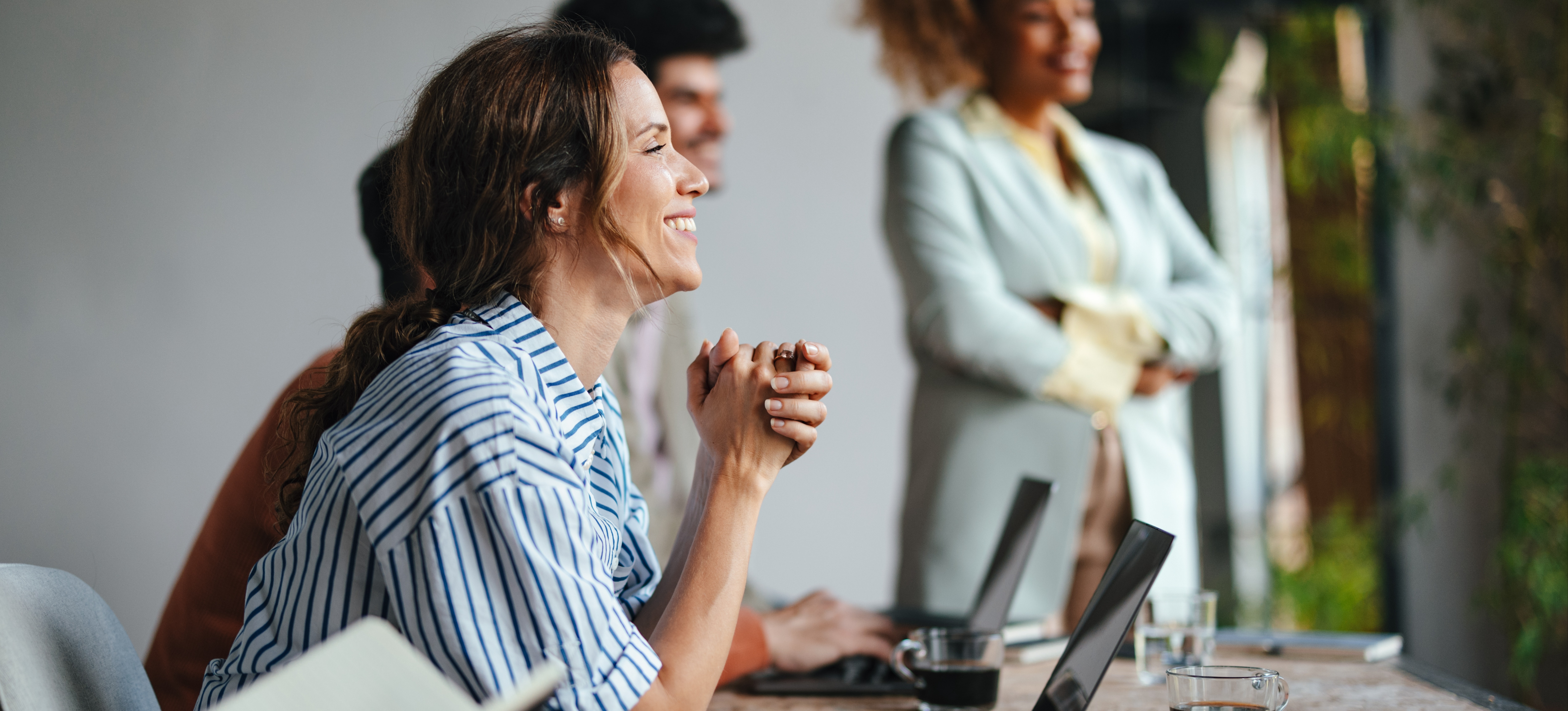 [Featured Image] A learner sitting in front of a laptop smiles as they listen to their in-person instructor, all part of the blended learning program they enrolled in.