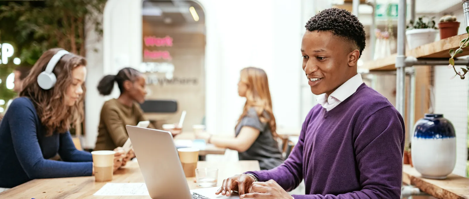 [Featured image] A recent high school graduate sits at a long table in a co-working space on a laptop researching their career options.