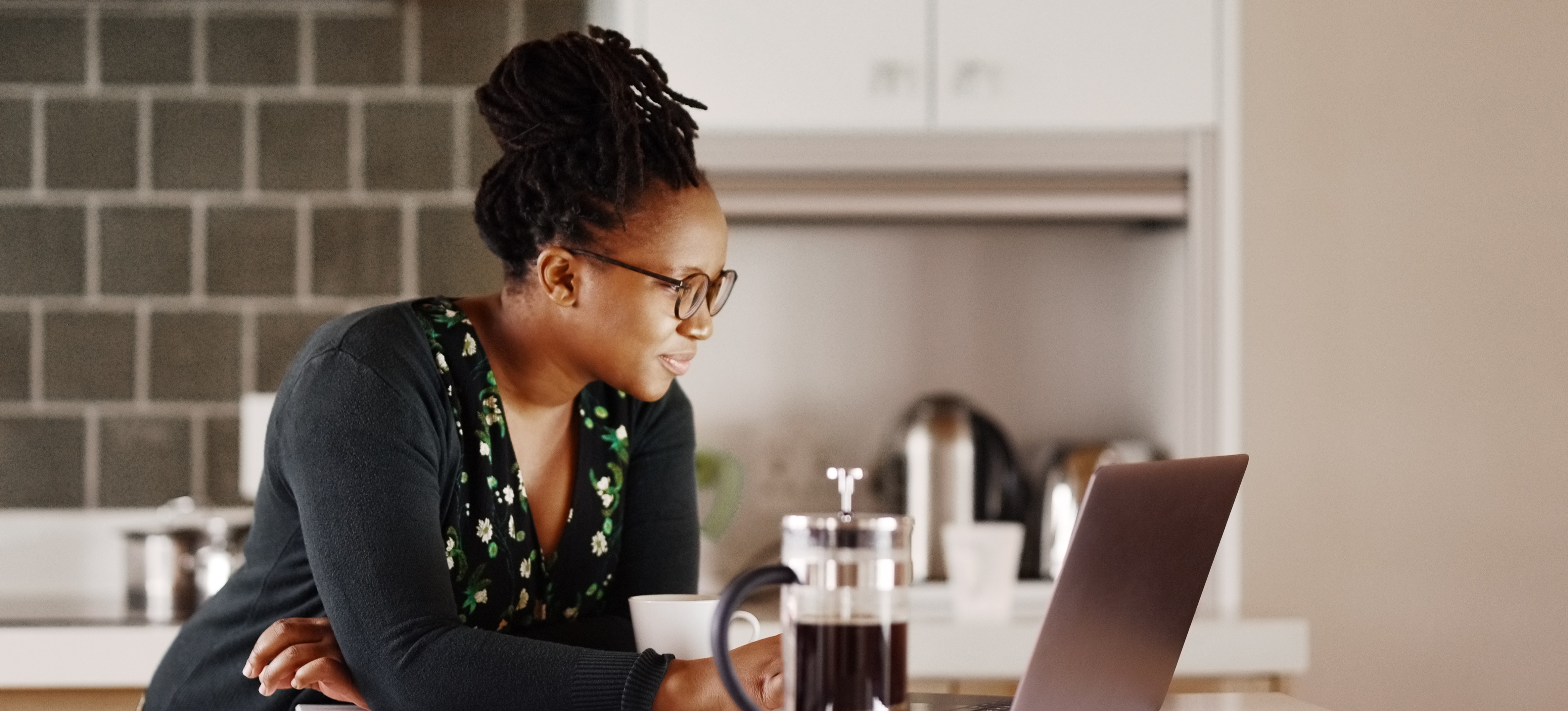 [Featured Image] A professional researches the average data visualization salary on a laptop while in their kitchen as they plan a potential career change.
