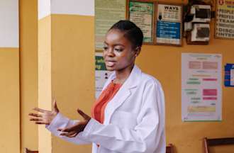 [Featured Image]:  Health Information Manager, wearing a white lab coat, standing outside the office, preparing information on patient's security.