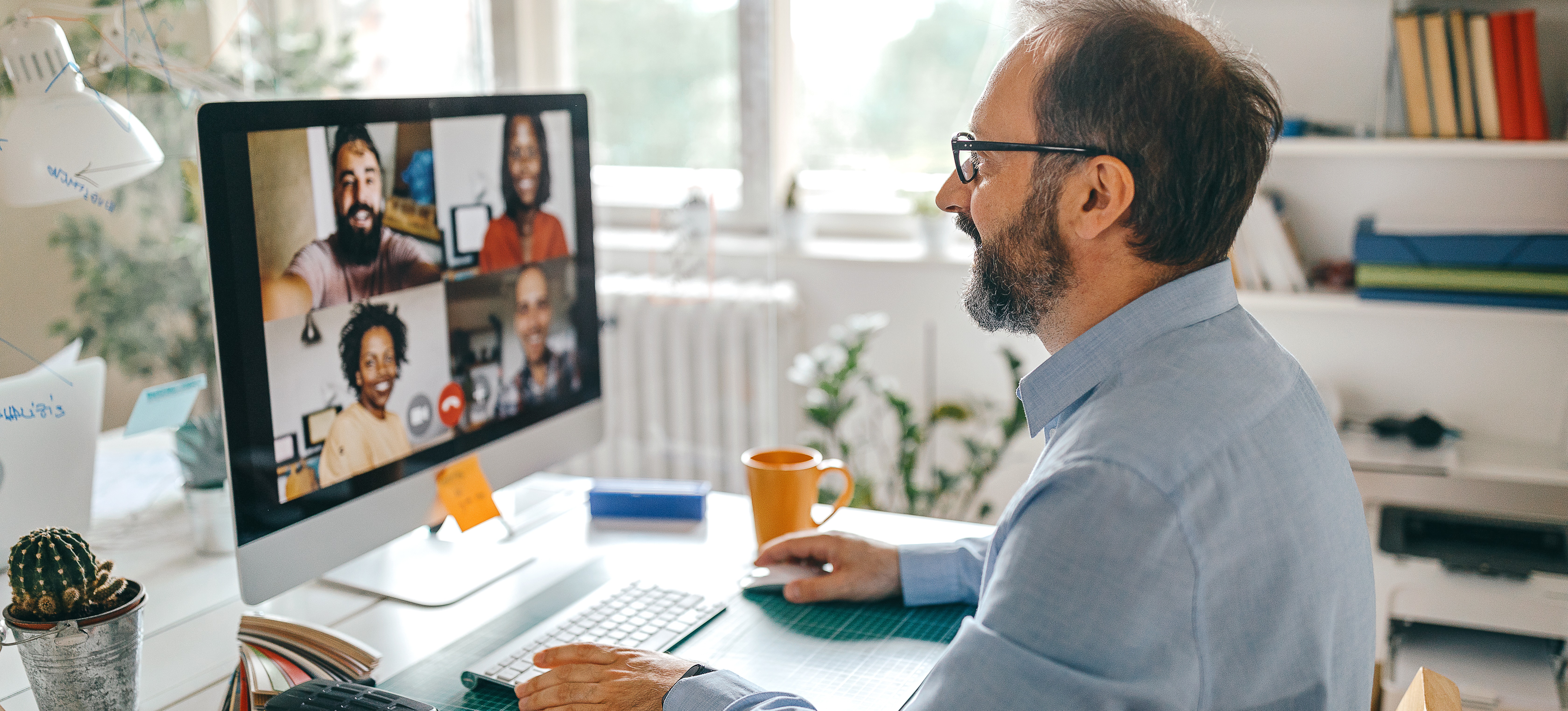 [Hauptbild] Ein Direktor, der weiß, wie man Remote-Teams leitet, hält eine Videokonferenz mit Kollegen aus seinem Homeoffice ab.