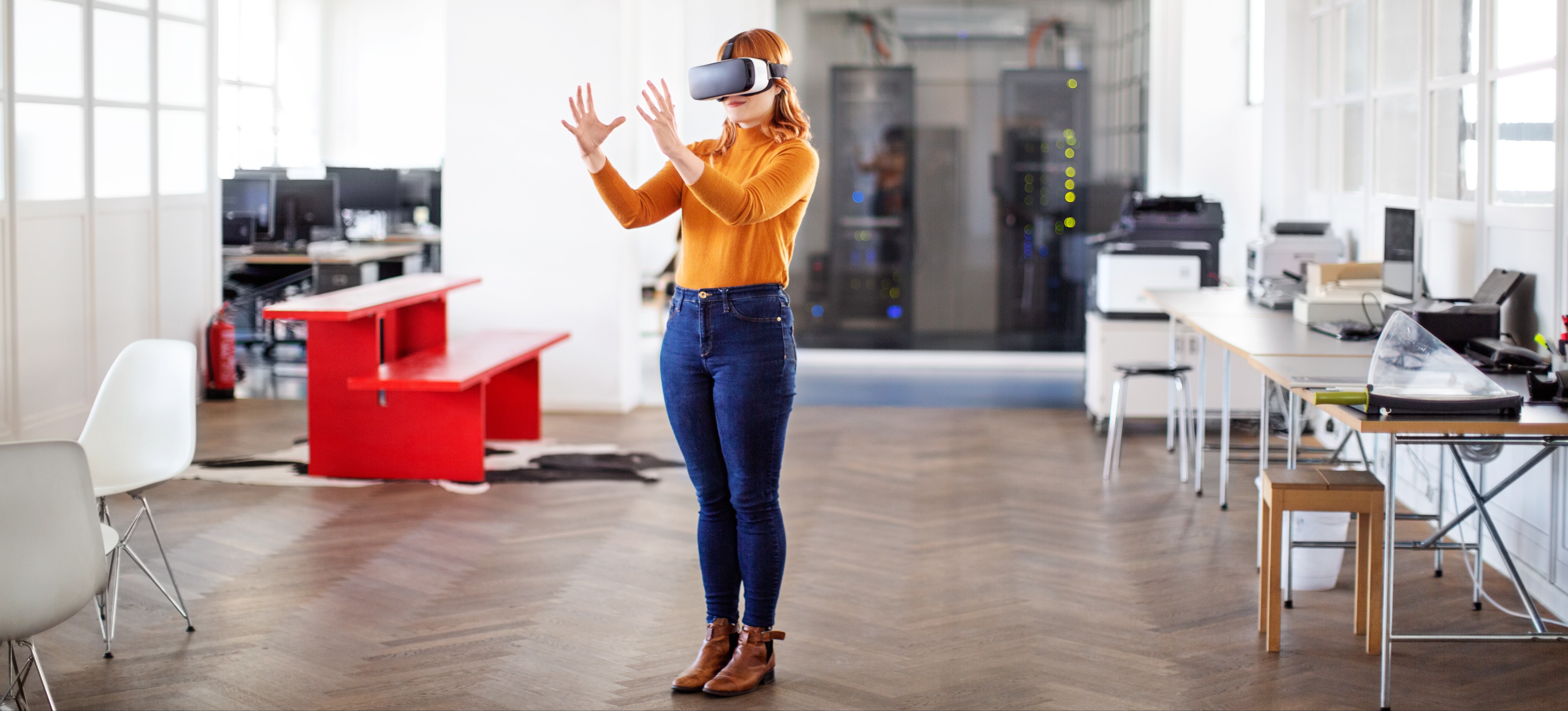 [Image en vedette] Une femme se tient dans un bureau et porte un casque de réalité virtuelle.