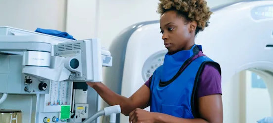 [Featured Image] A worker wearing a protective vest works with radiologic equipment. 