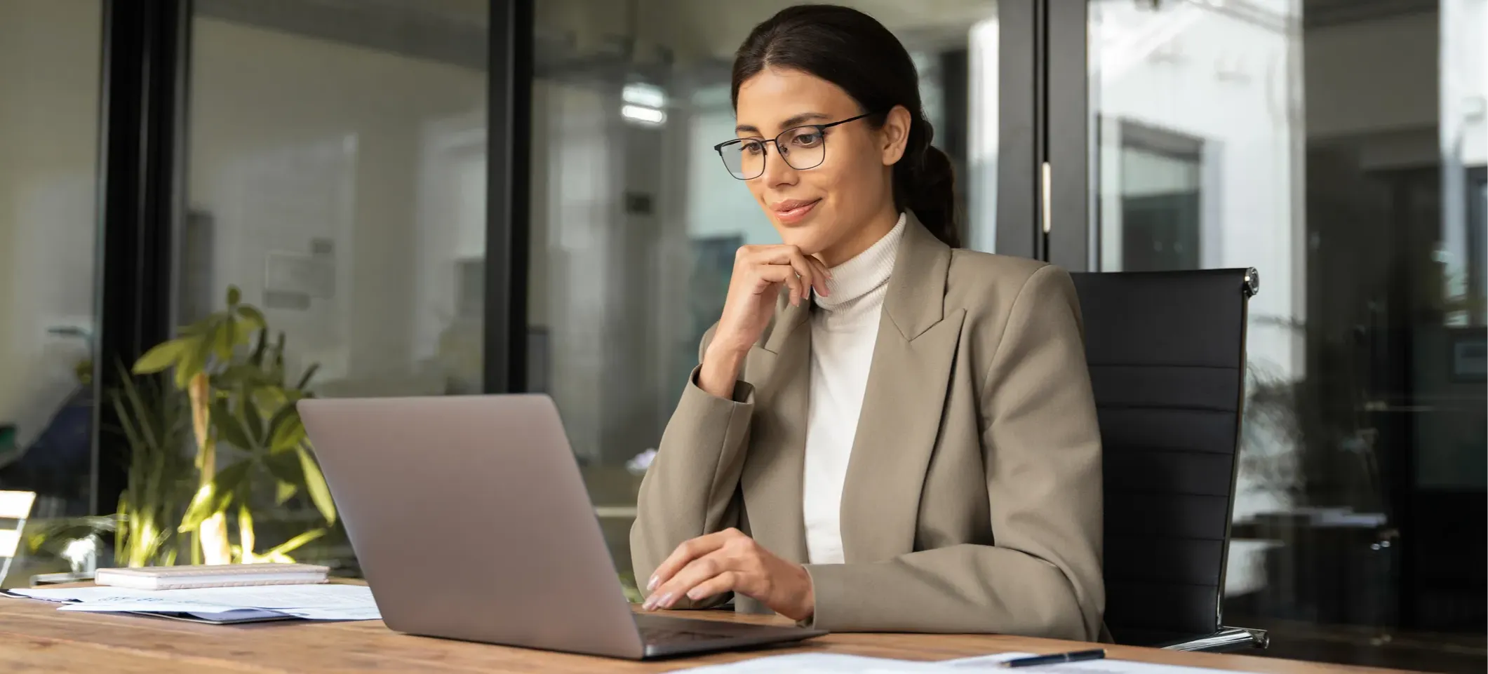 [Featured Image]: A person sitting at a table works on a laptop to write a ChatGPT letter of recommendation for a colleague.
