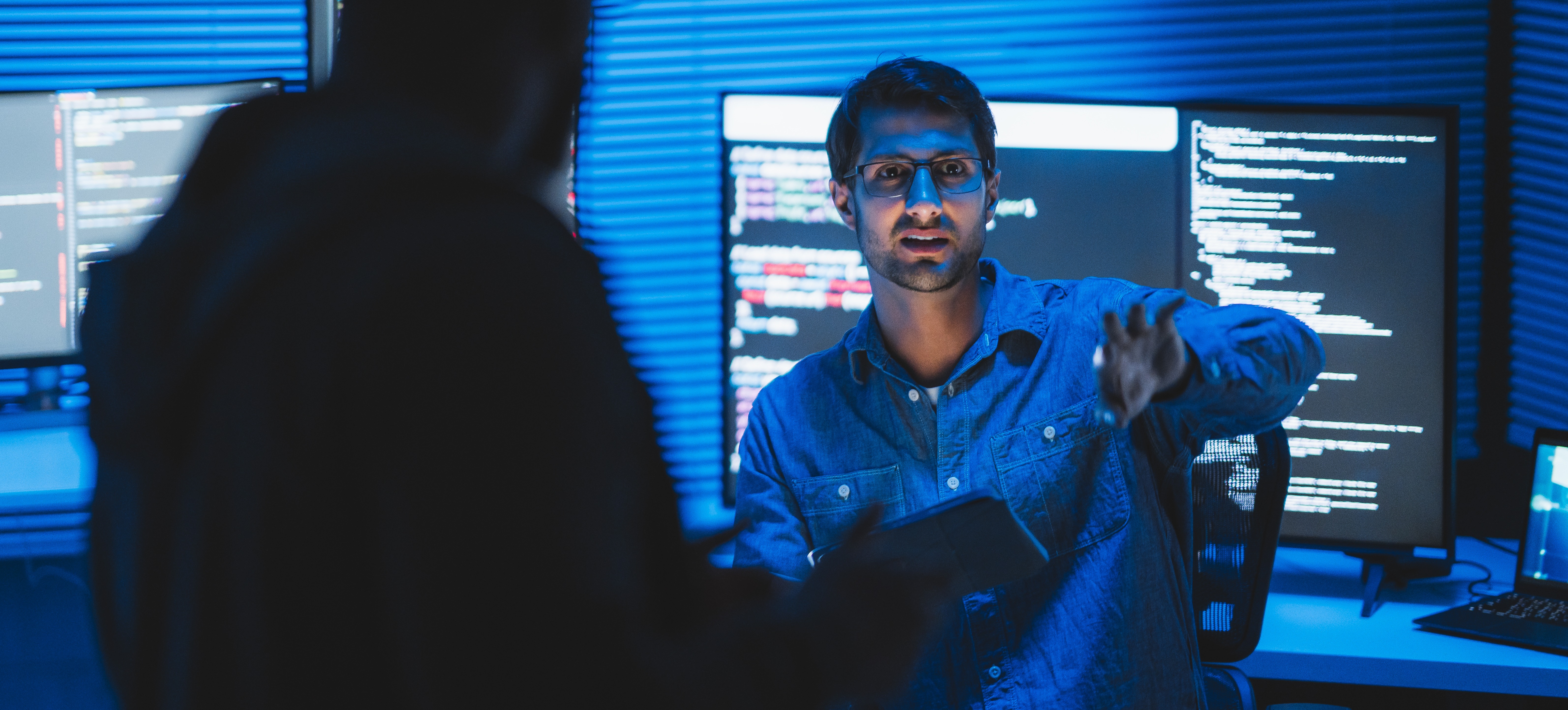 [Featured Image] A cybersecurity analyst sitting in front of several computer monitors displaying data explains their findings.