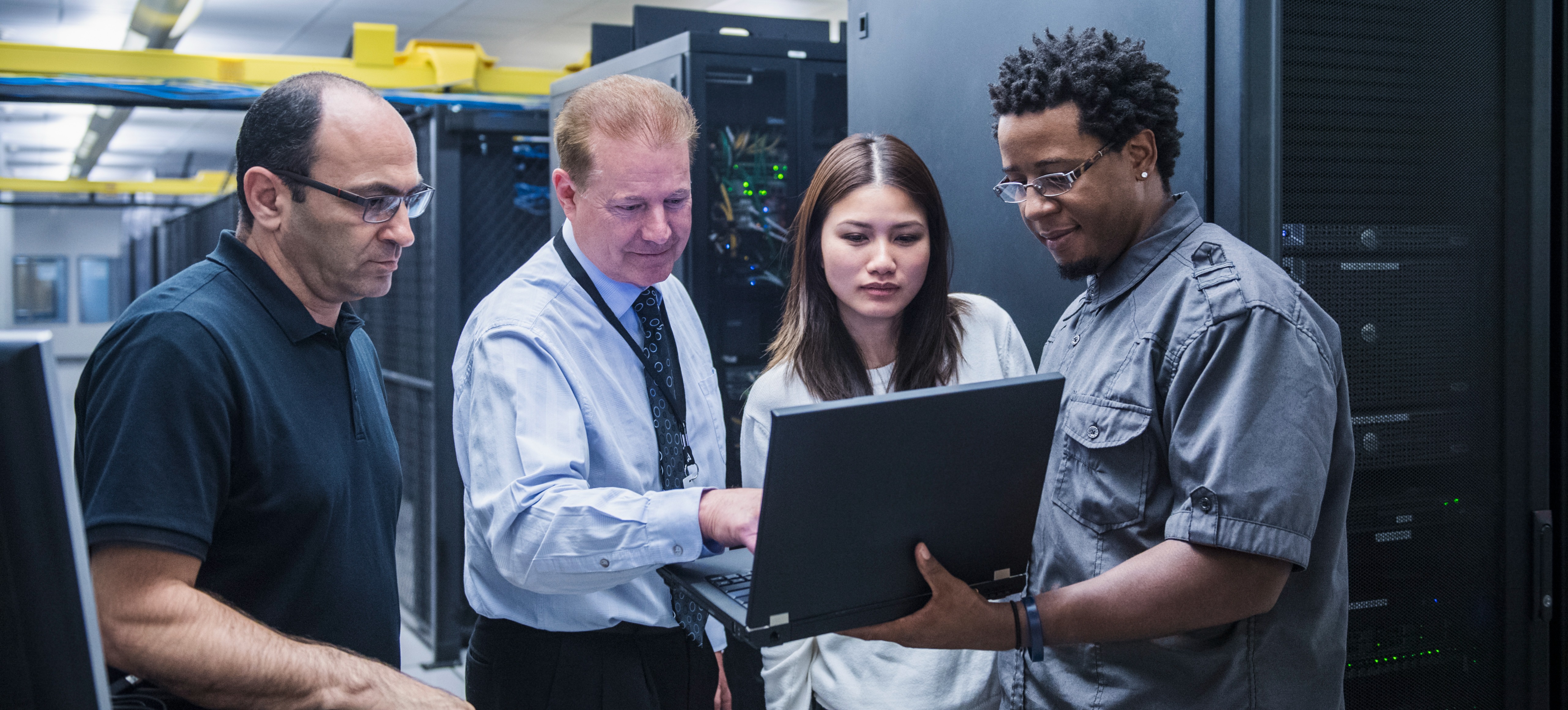 [Featured Image] An information technology consultant meets with clients in the server room to discuss IT services.
