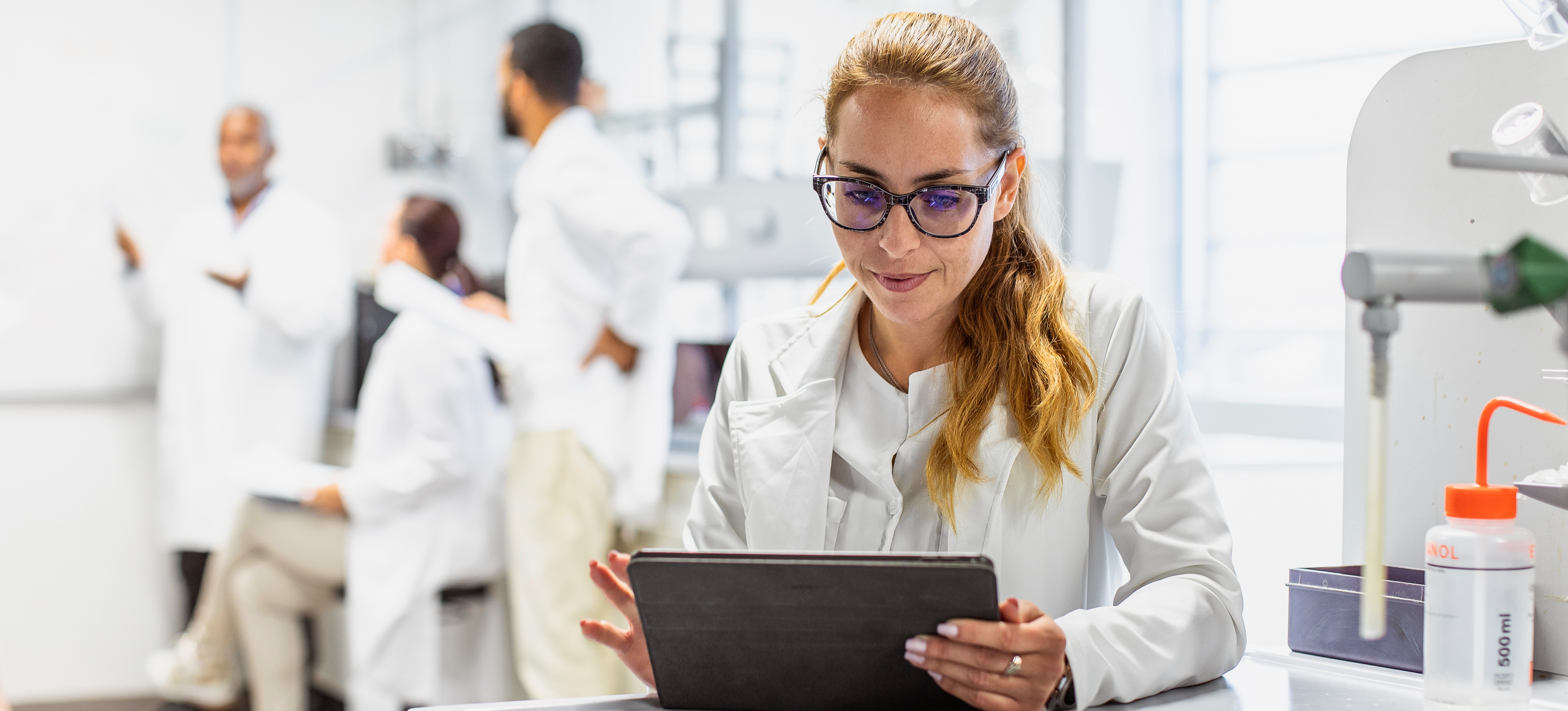 [Featured Image] A scientist working in a lab uses a tablet to look over synthetic data. 