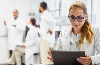 [Featured Image] A scientist working in a lab uses a tablet to look over synthetic data. 