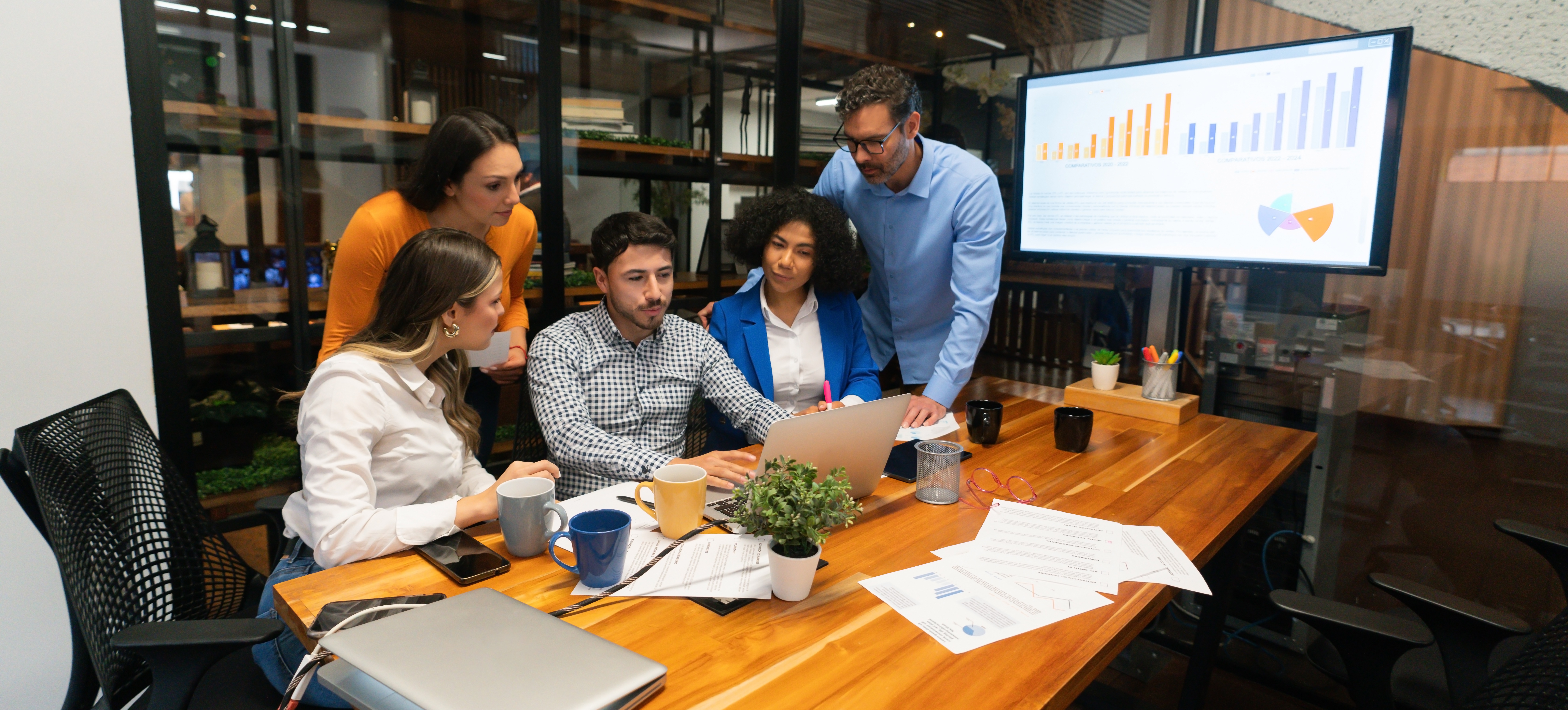 [Featured Image] A search engine marketing team huddles around a crowded conference table to discuss their next campaign.
