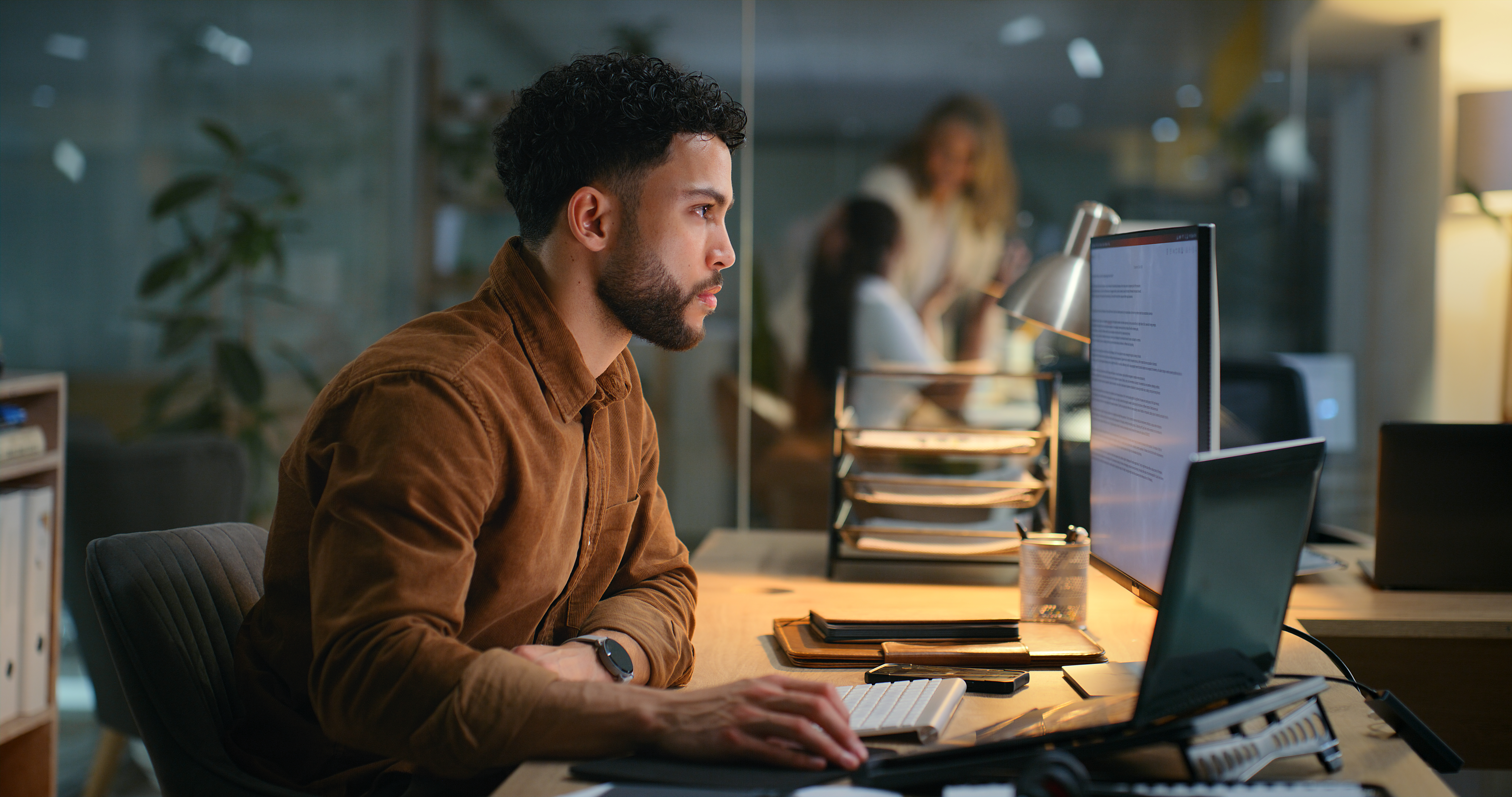 [Featured Image] A cloud inventory manager works on a desktop computer with two screens, using cloud inventory software to analyze and generate real-time reports. 