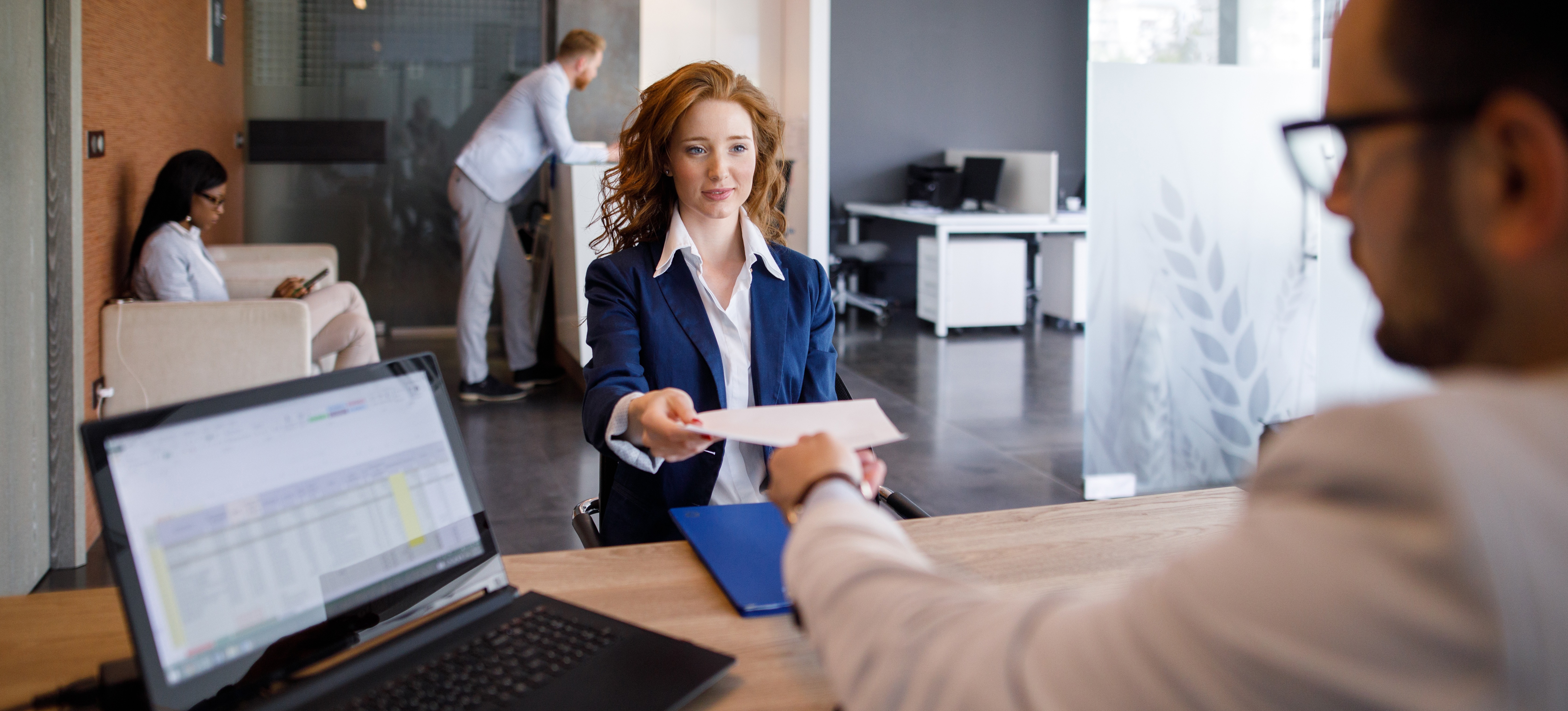 [Featured image]: A job applicant hands their front-end developer resume to a manager seated behind a desk.
