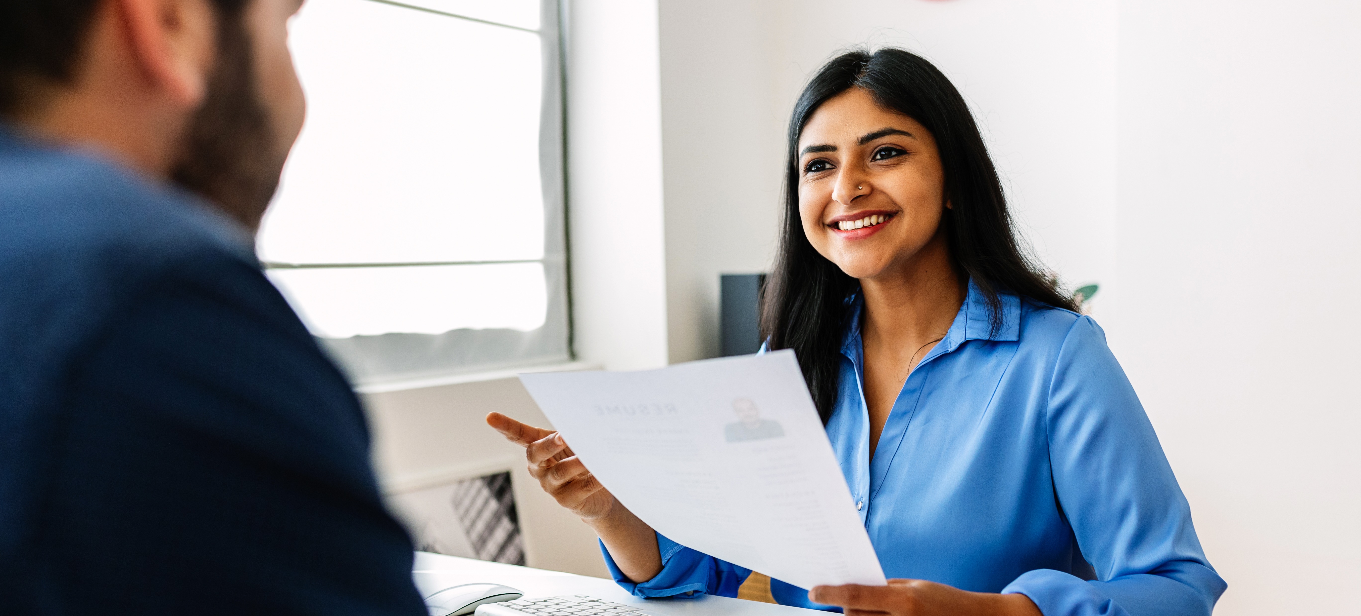 [Featured Image] An HR representative with a human resources certification talks to a job applicant during an interview.

