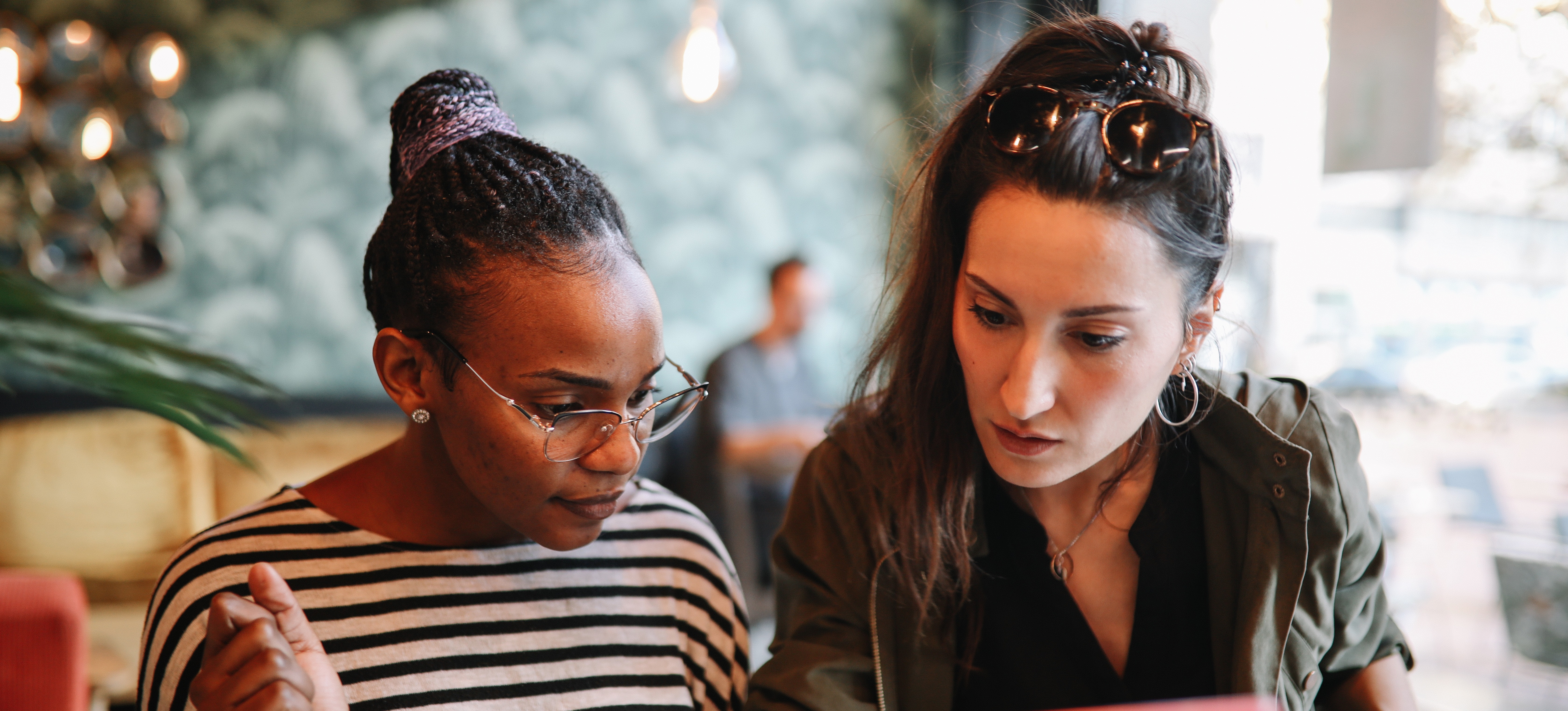 [Featured Image] Two natural language processing professionals sit together and examine code on a laptop.
