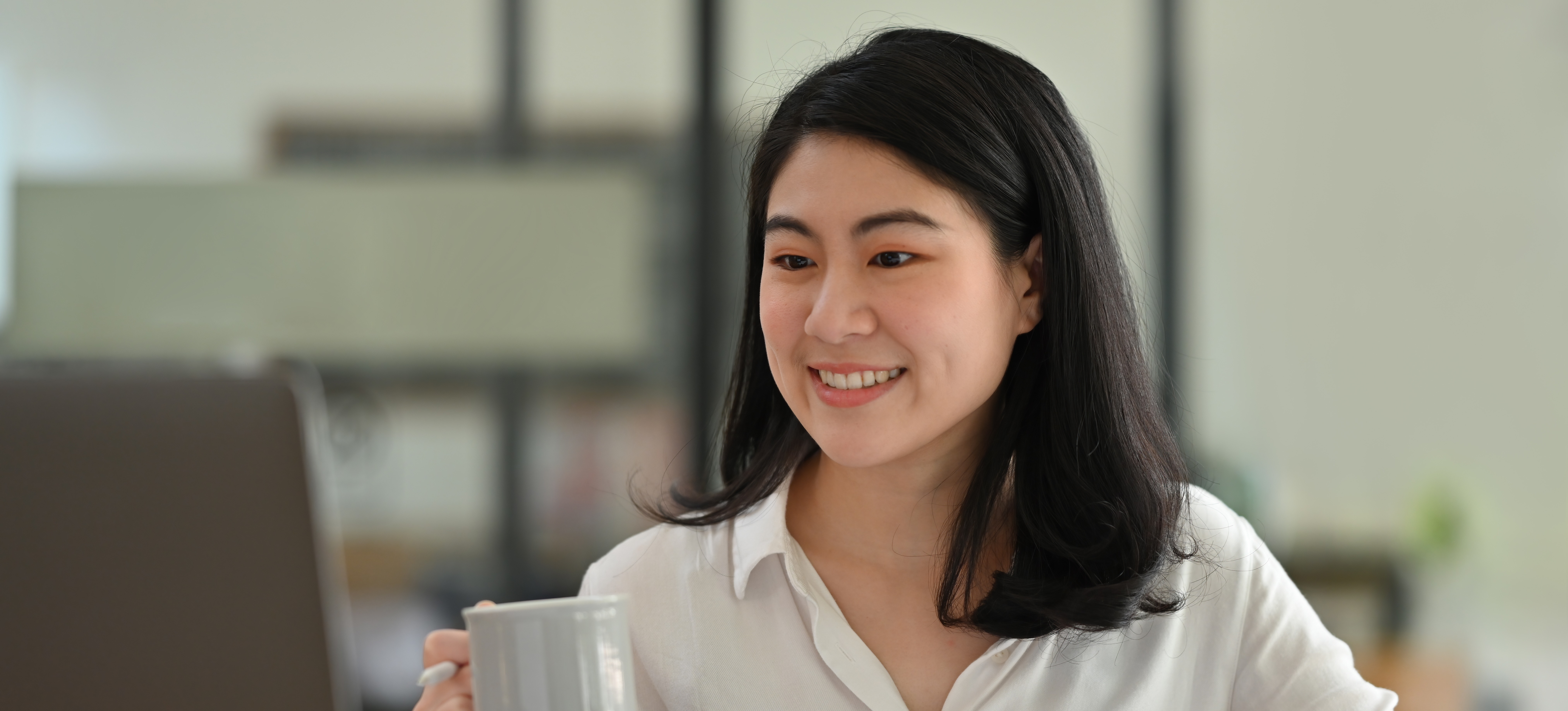 [Featured Image] A smiling person holding a coffee cup looks at their laptop and discovers how to learn Excel with AI.