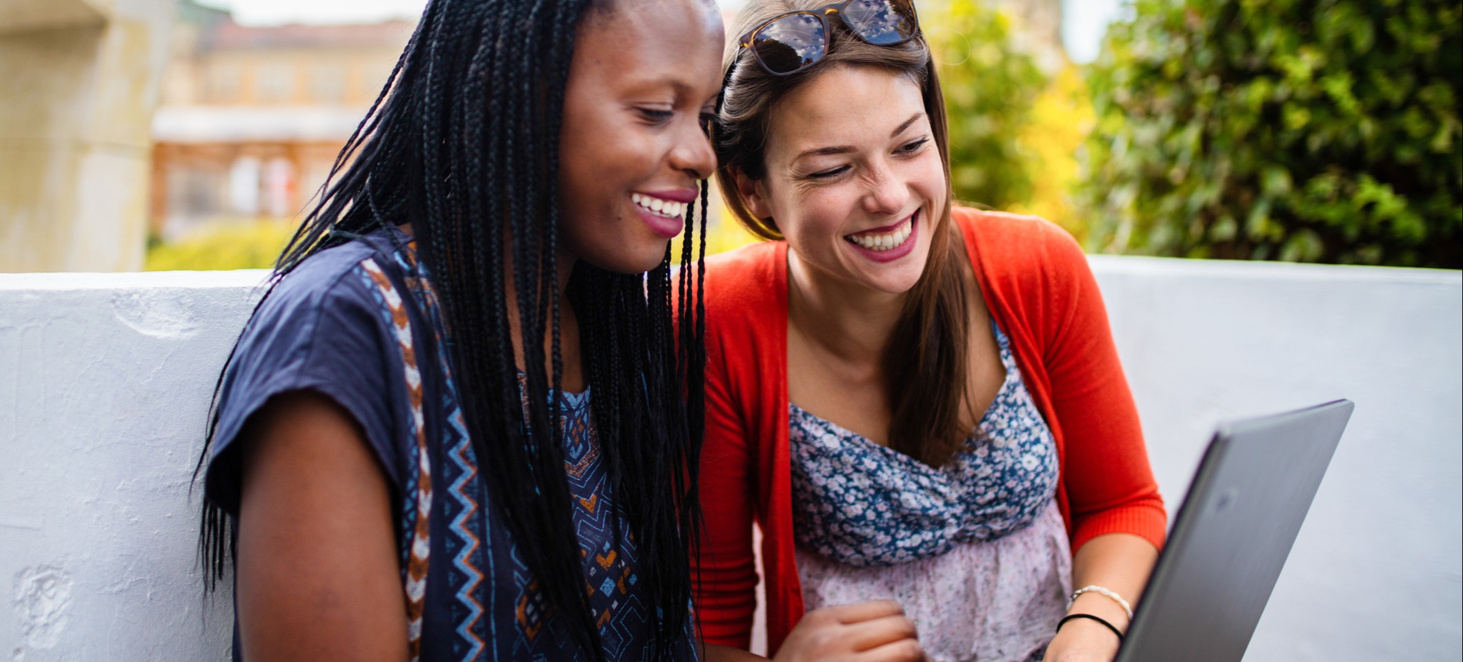 [Imagen destacada] Dos estudiantes de la licenciatura de finanzas exploran sus opciones profesionales en un ordenador portátil al aire libre en el campus.