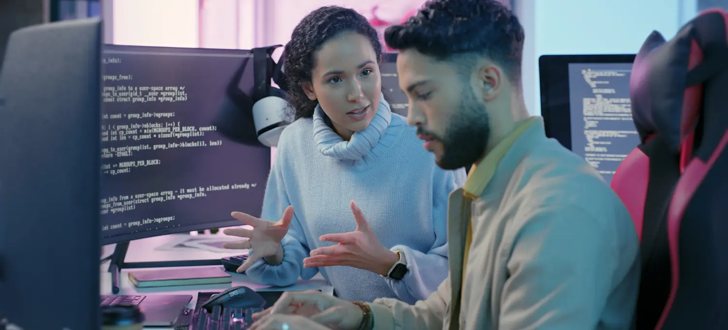 [Featured Image] Two programmers work together to make corrections to the codebase during a code review.

