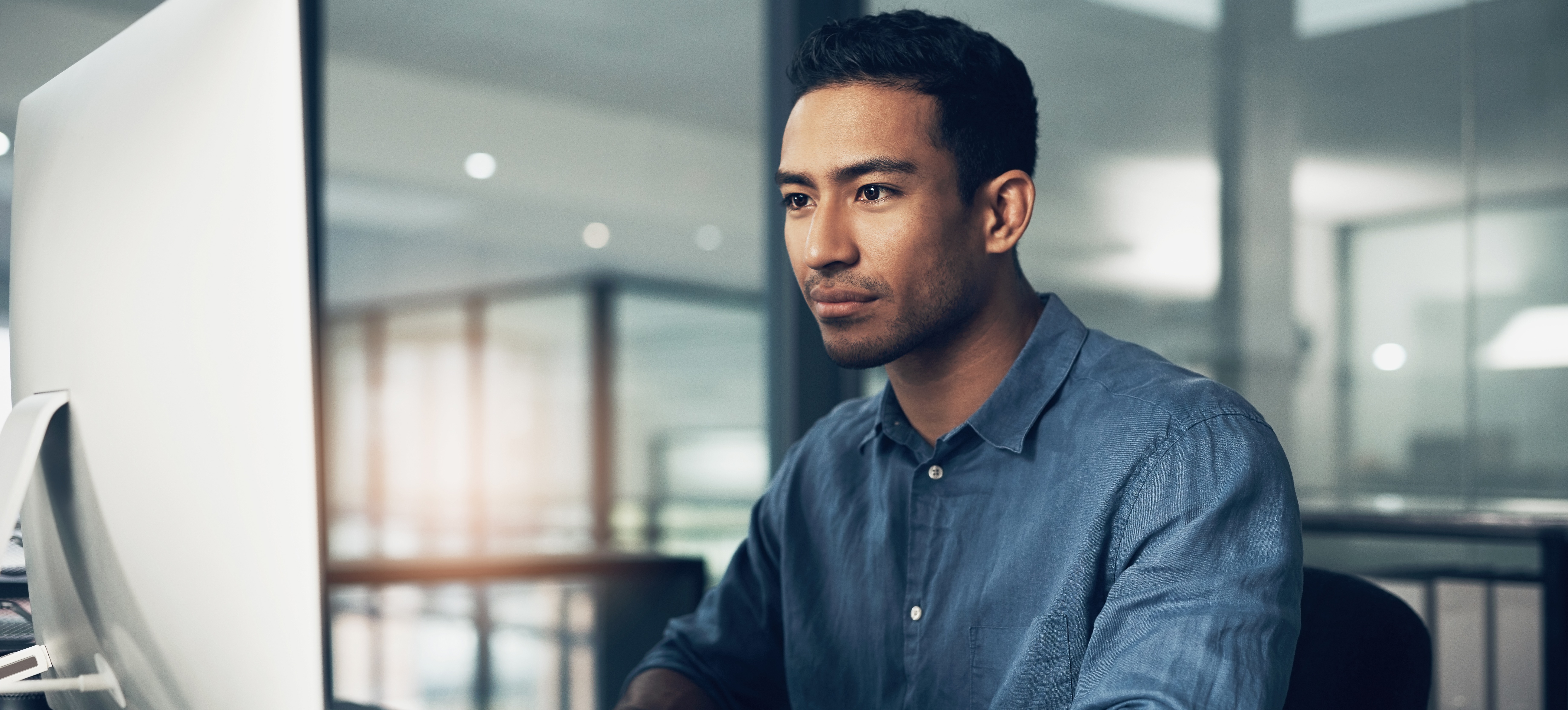 [Featured image] An AI engineer in a blue shirt reviews AI ethics standards while sitting in front of a desktop computer monitor.