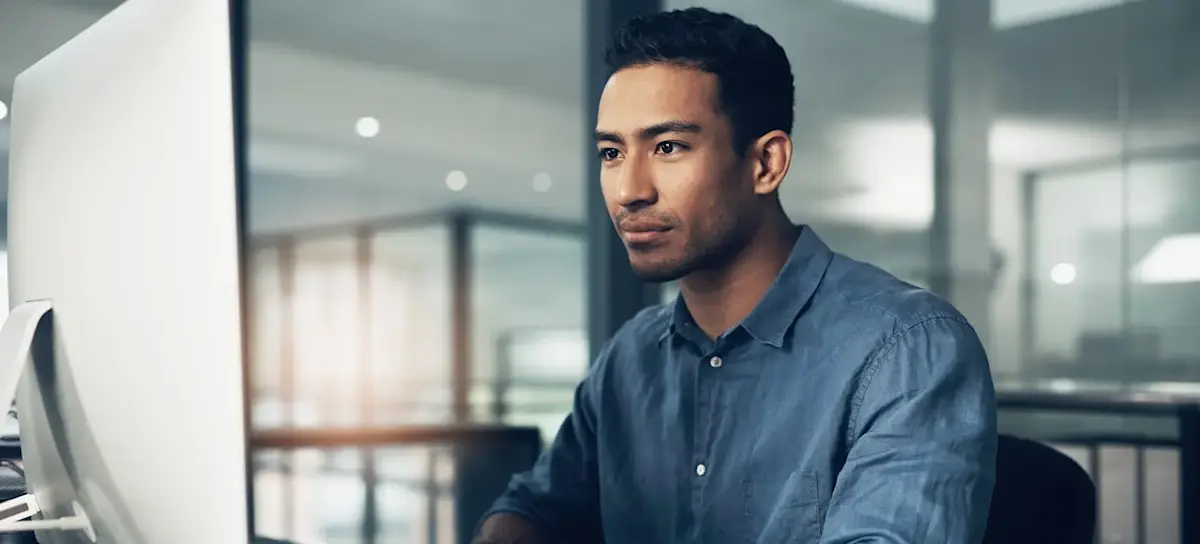 [Featured image] An AI engineer in a blue shirt reviews AI ethics standards while sitting in front of a desktop computer monitor.