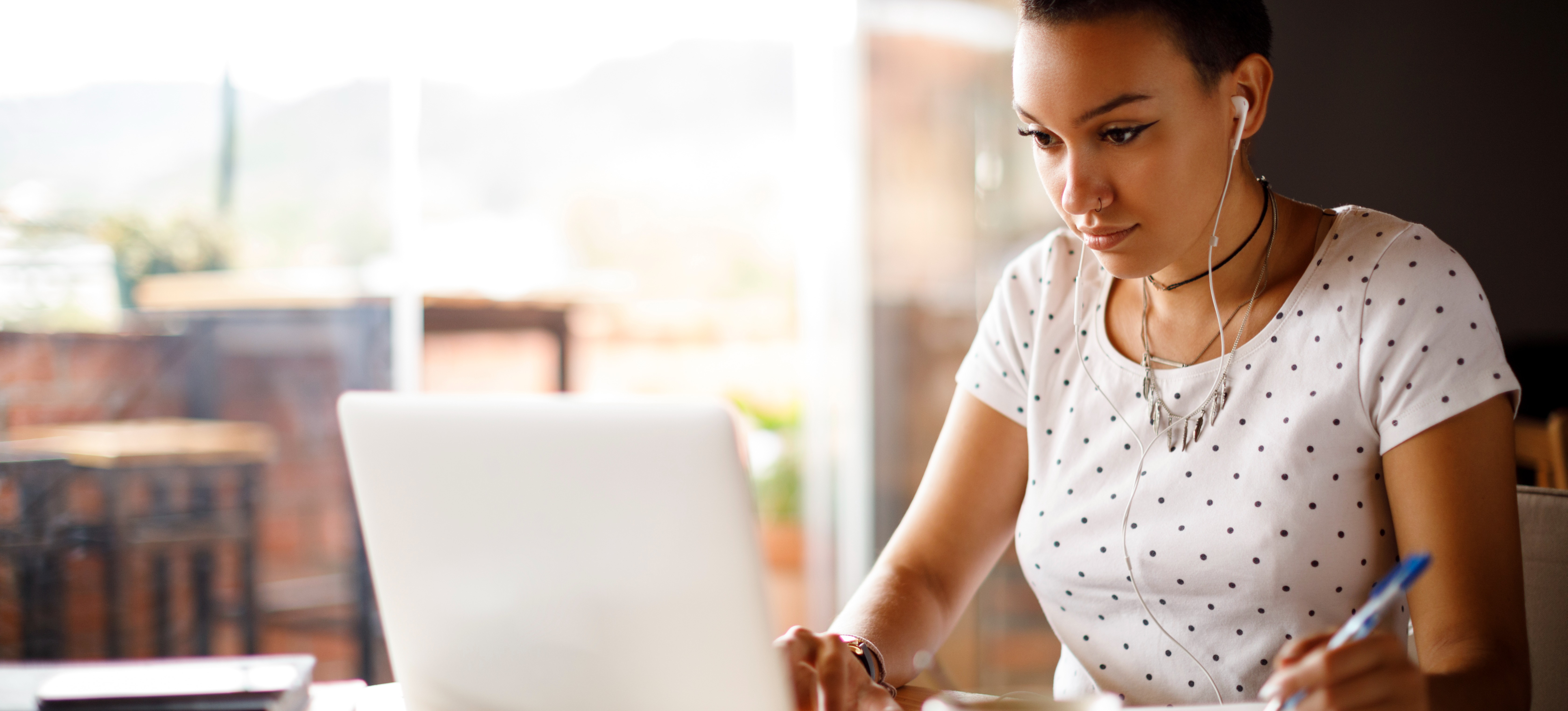 [Featured Image] A young person sits at their laptop with a cup of coffee and researches universities that do not require GCSEs.
