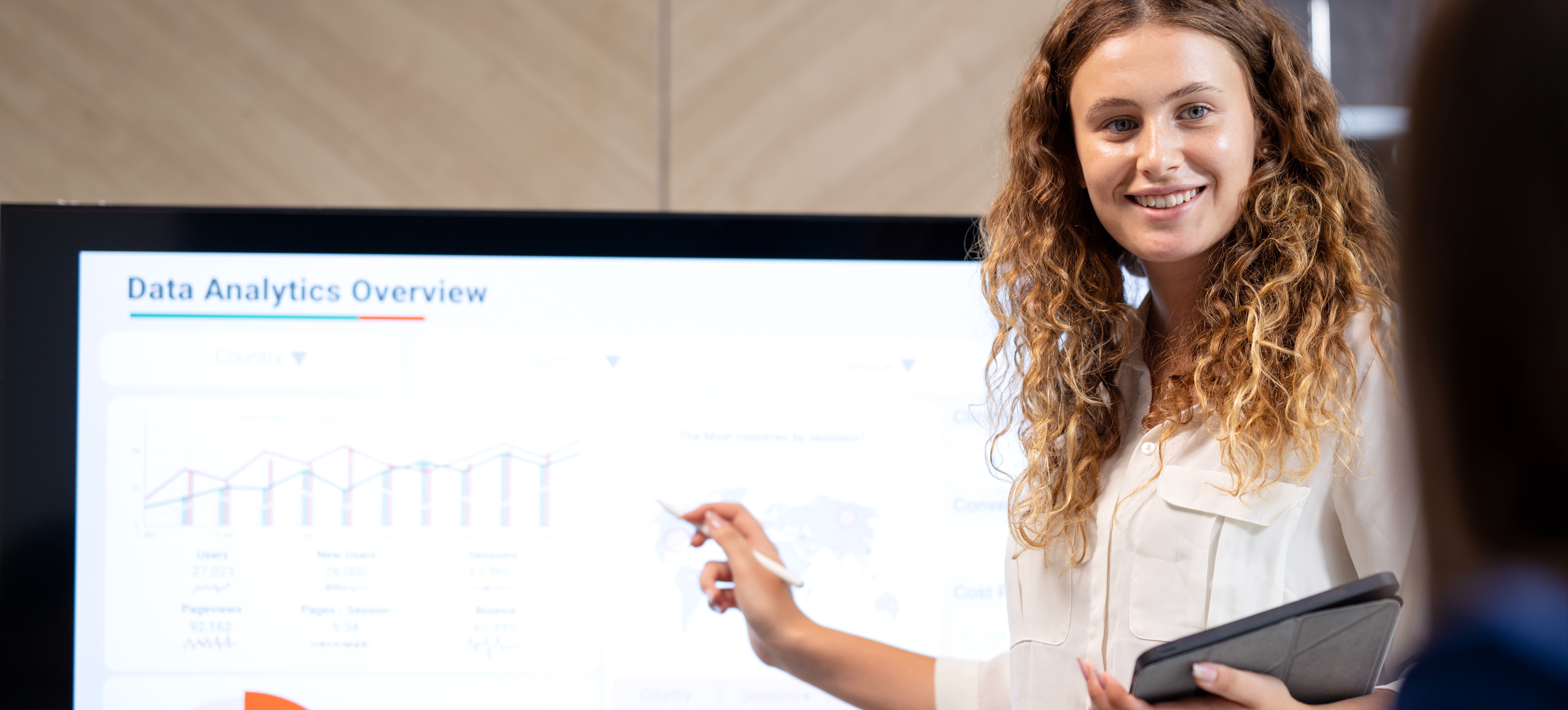 [Featured Image] A data analyst points at a large screen with charts and graphs about data analytics and lambda architecture.
