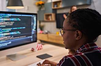 [Featured image]:  QA Tester, working on a desktop computer, identifying and analyzing problems during the debugging process of the software. 