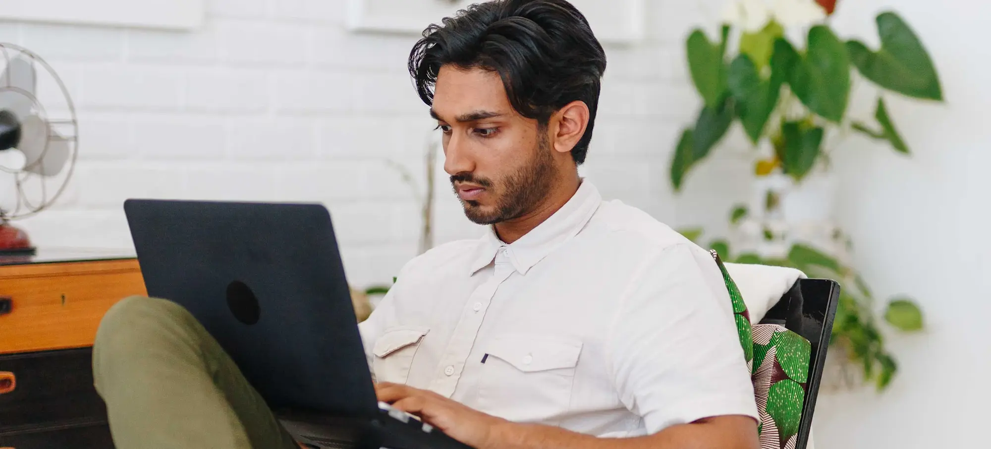 [Featured image] A man wearing a white shirt looking at a laptop screen and typing.