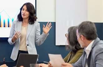 [Featured image] A woman in a business suit presents a go-to-market strategy to her team in a conference room.