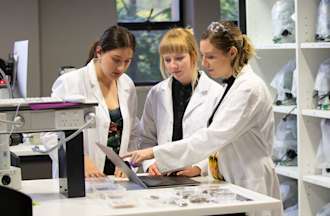 [Featured Image] A Certified Nursing Assistant works in a medical lab alongside her colleagues.