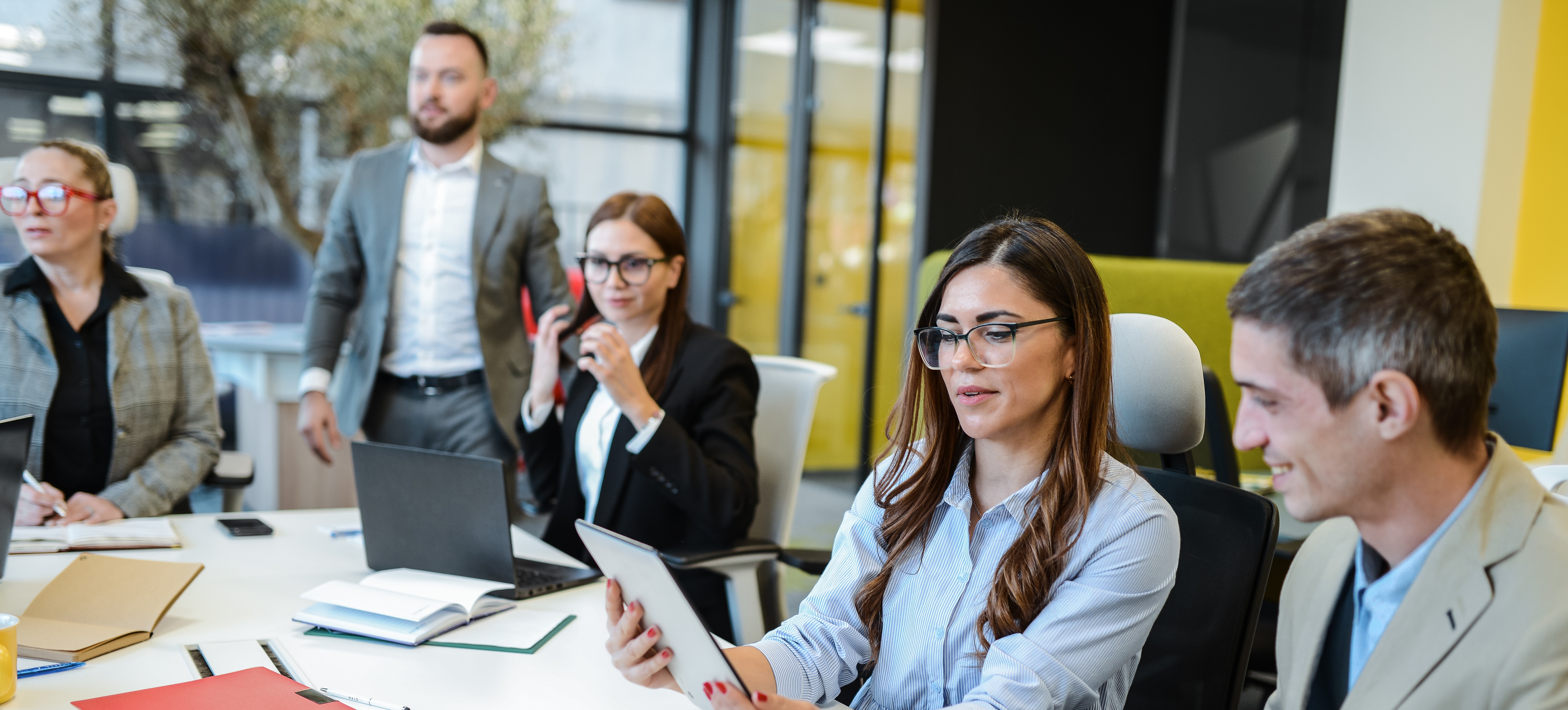 [Featured image] Project team members sit at a boardroom table with their laptops and tablets, discussing the project using conceptual data modeling.